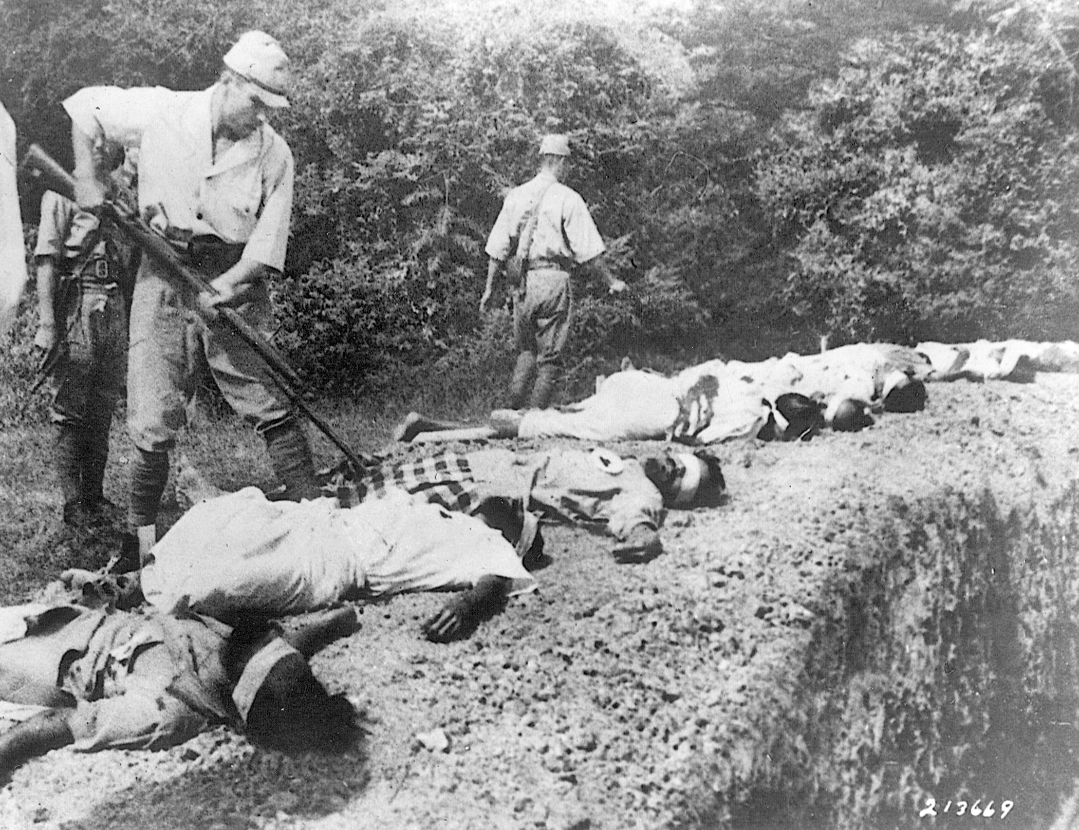 A Japanese soldier bayonets the body of a prisoner, one of several summarily executed by firing squad.