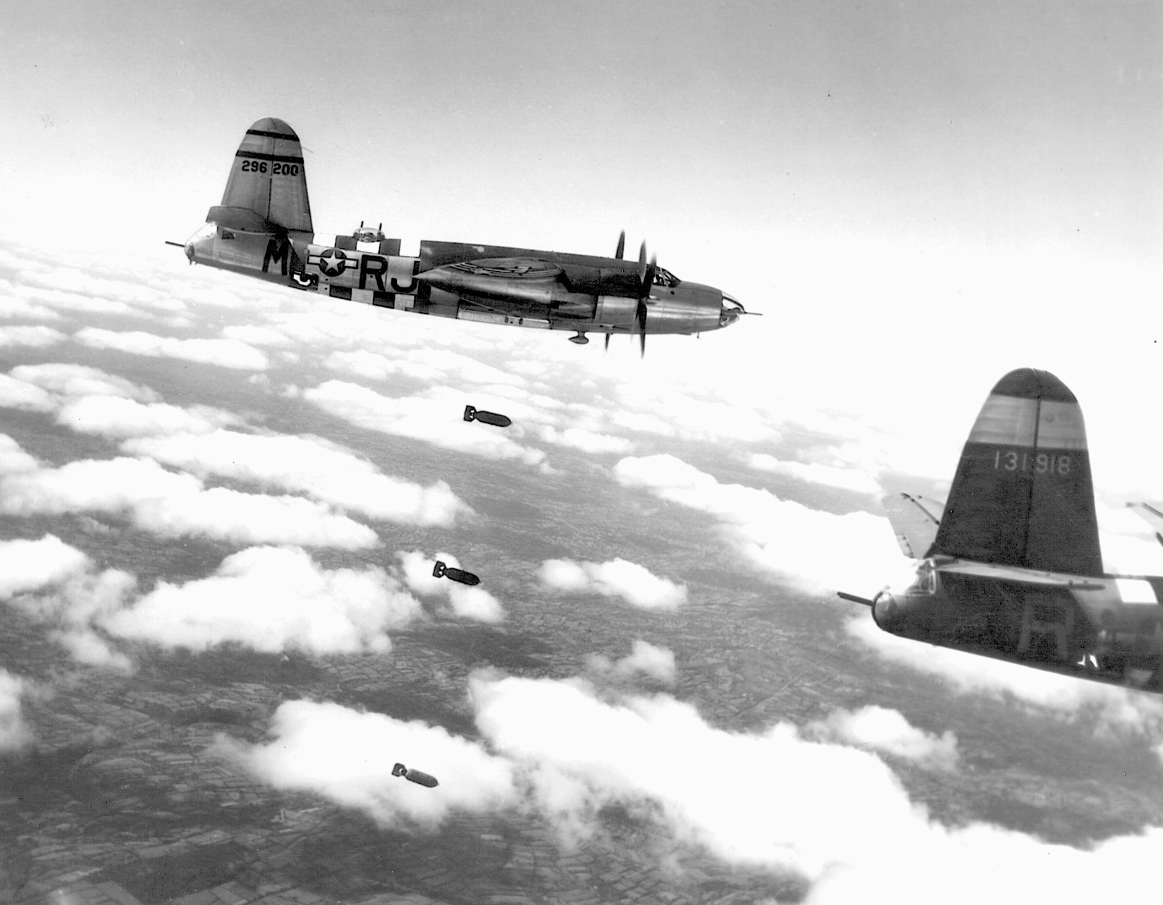   Flying above Torigni, France, a B-26 Silver Streak Marauder releases its bombload.