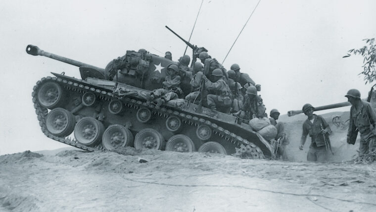 An M-26 tank—manned by soldiers of the 9th Infantry Regiment—is poised to counter an enemy attempt to cross the Naktong River in Korea, September 1950.