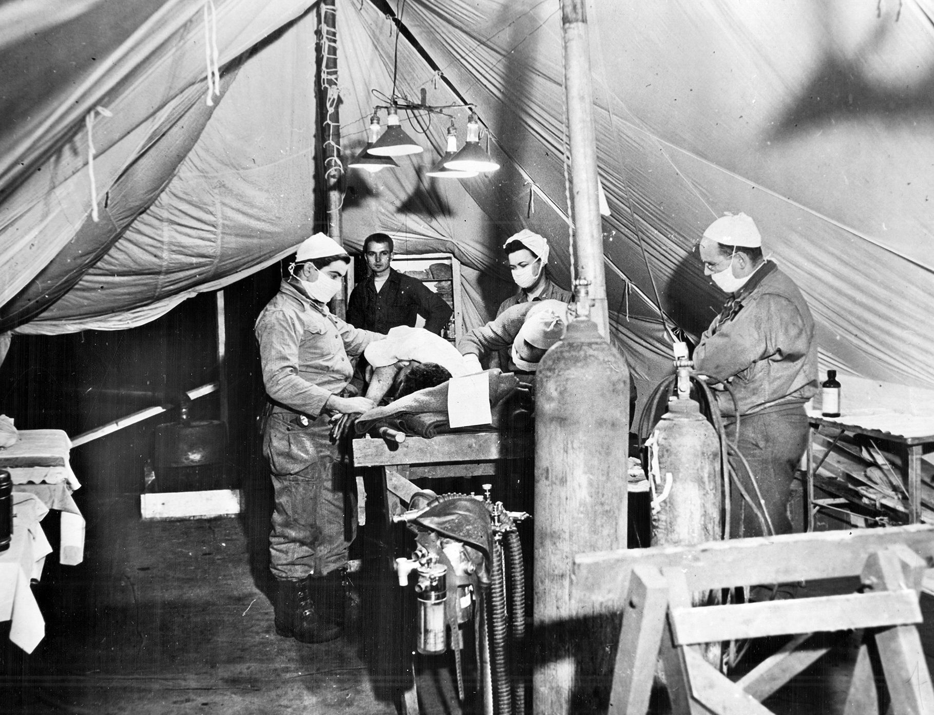 Two doctors, a nurse, and other personnel operate on a wounded GI at a field hospital during the Battle of the Bulge. Such surgery so close to the combat areas often meant the difference between life and death for seriously injured soldiers.
