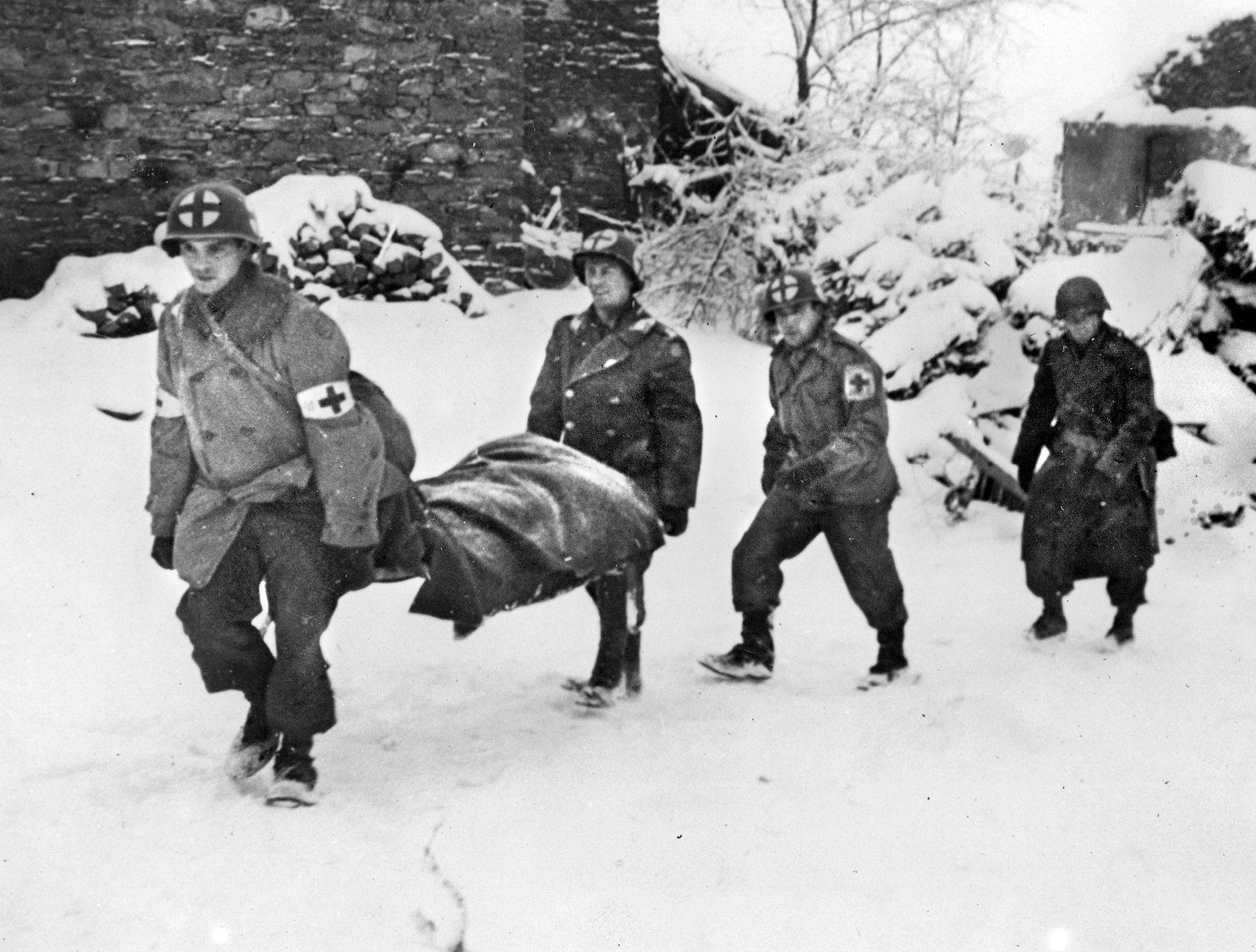 Army medics move a wounded soldier to safety during the Battle of the Bulge. Officers of the 326th Airborne Medical Company were worried that their position might be overrun, but Gen. Anthony McAuliffe, commanding the 101st Airborne Division, gave them repeated assurances that they were secure.