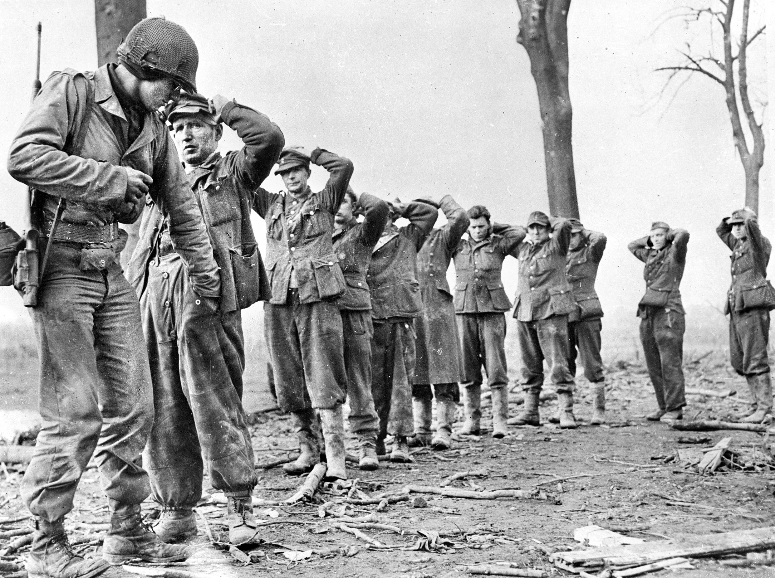  An American soldier searches surrendering German troops for weapons. Cohn served with the Prisoner of War Team 66, interviewing German soldiers and officers for intelligence and assessed buildings for use in prosecuting war criminals. 