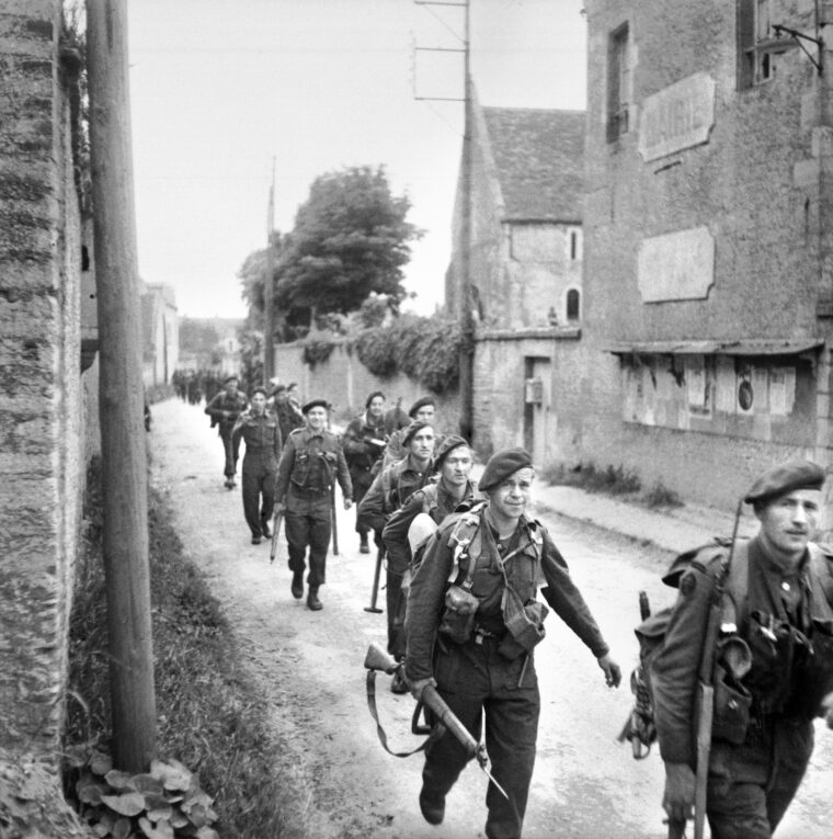 Lord Lovat’s commandos make their way through the French village of Colleville-sur-Orne on their way to link up with the glider troops of the British 6th Airborne at the Pegasus Bridge over the Caen Canal.