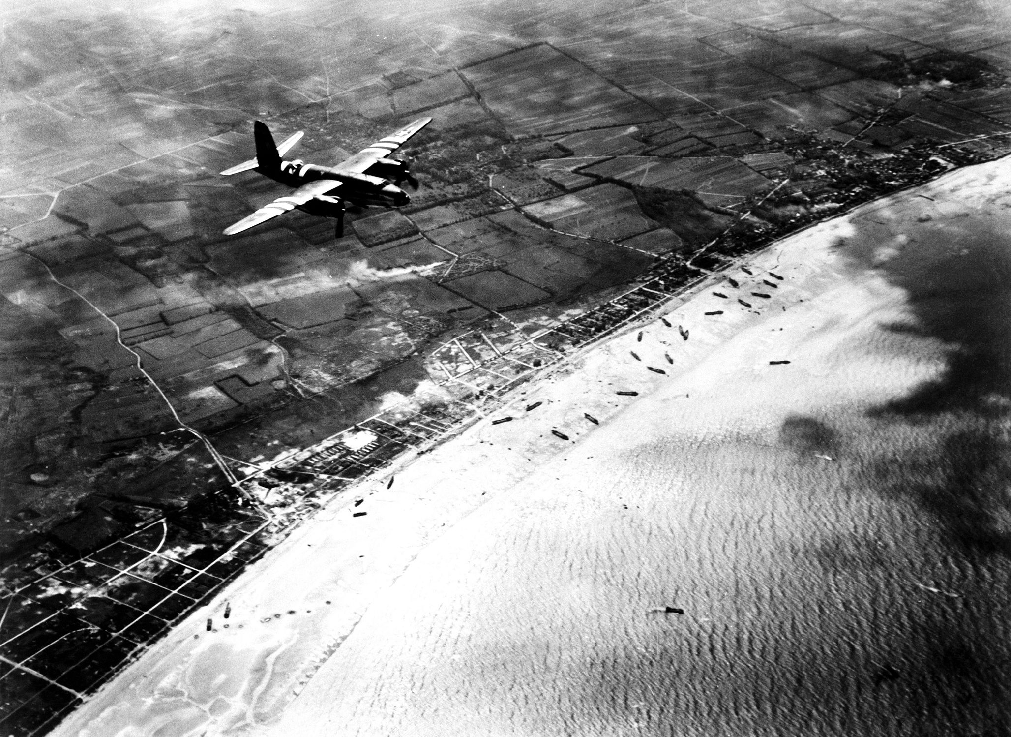 An American Martin B-26 Marauder bomber flies over Sword Beach en route to its airfield in Britain on D-Day. Lyon-sur-Met is shown at upper right.