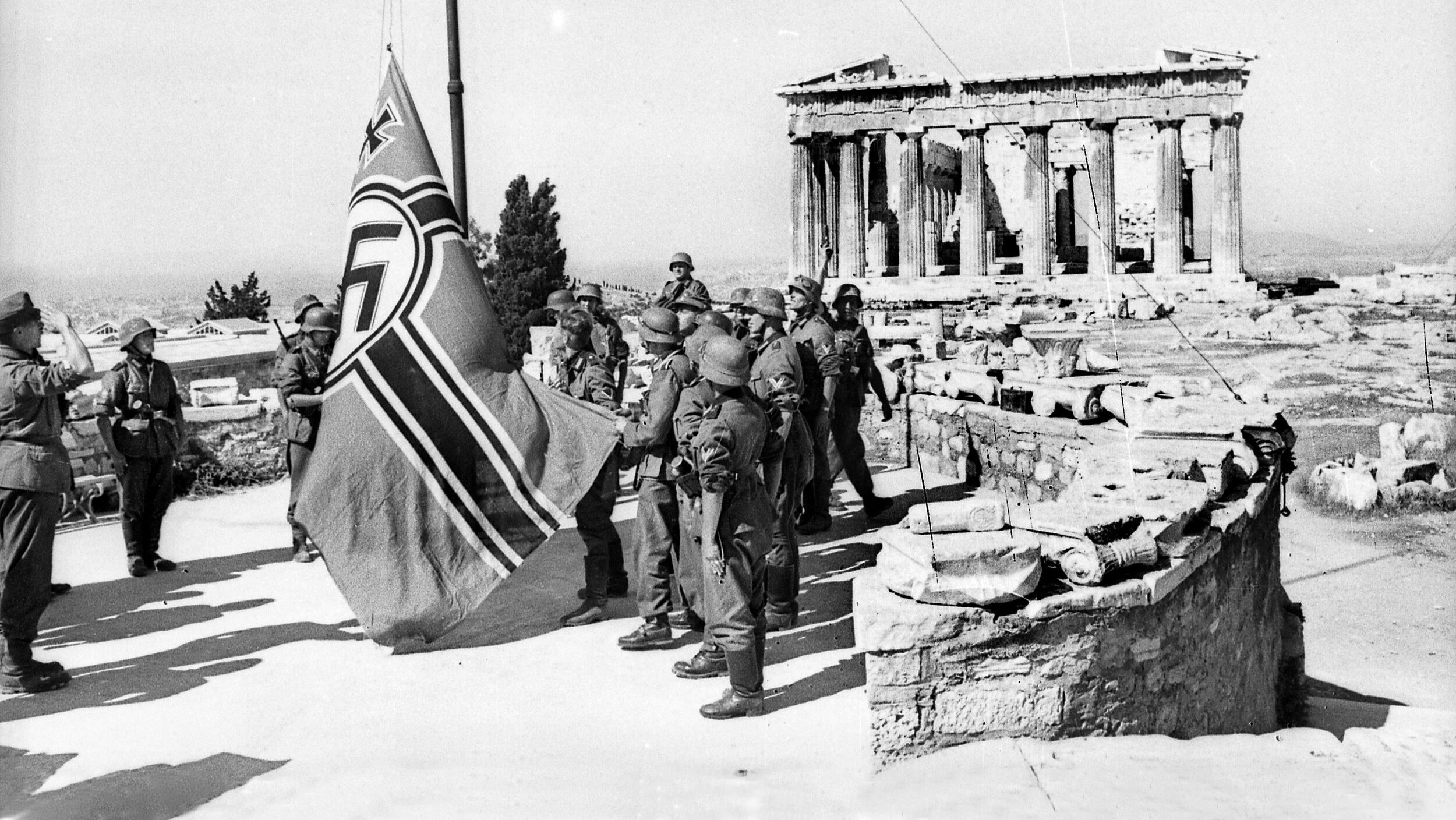 After having failed to conquer his long-time rival Greece, Italian dictator Benito Mussolini asked Axis partner Adolf Hitler for help. Here, German soldiers raise the German war banner atop the Acropolis in Athens after forcing the Greeks to surrender on April 27, 1941. Terrible atrocities by the Germans against the Greek populace followed.