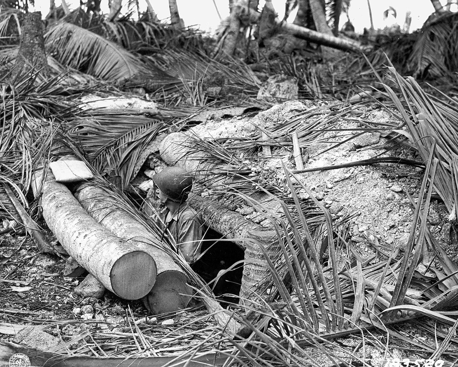 An American soldier peers from a reinforced bunker recently occupied by the Japanese at Makin in the Gilbert Islands. Makin was captured after landings on November 20, 1943, during Operation Galvanic. 