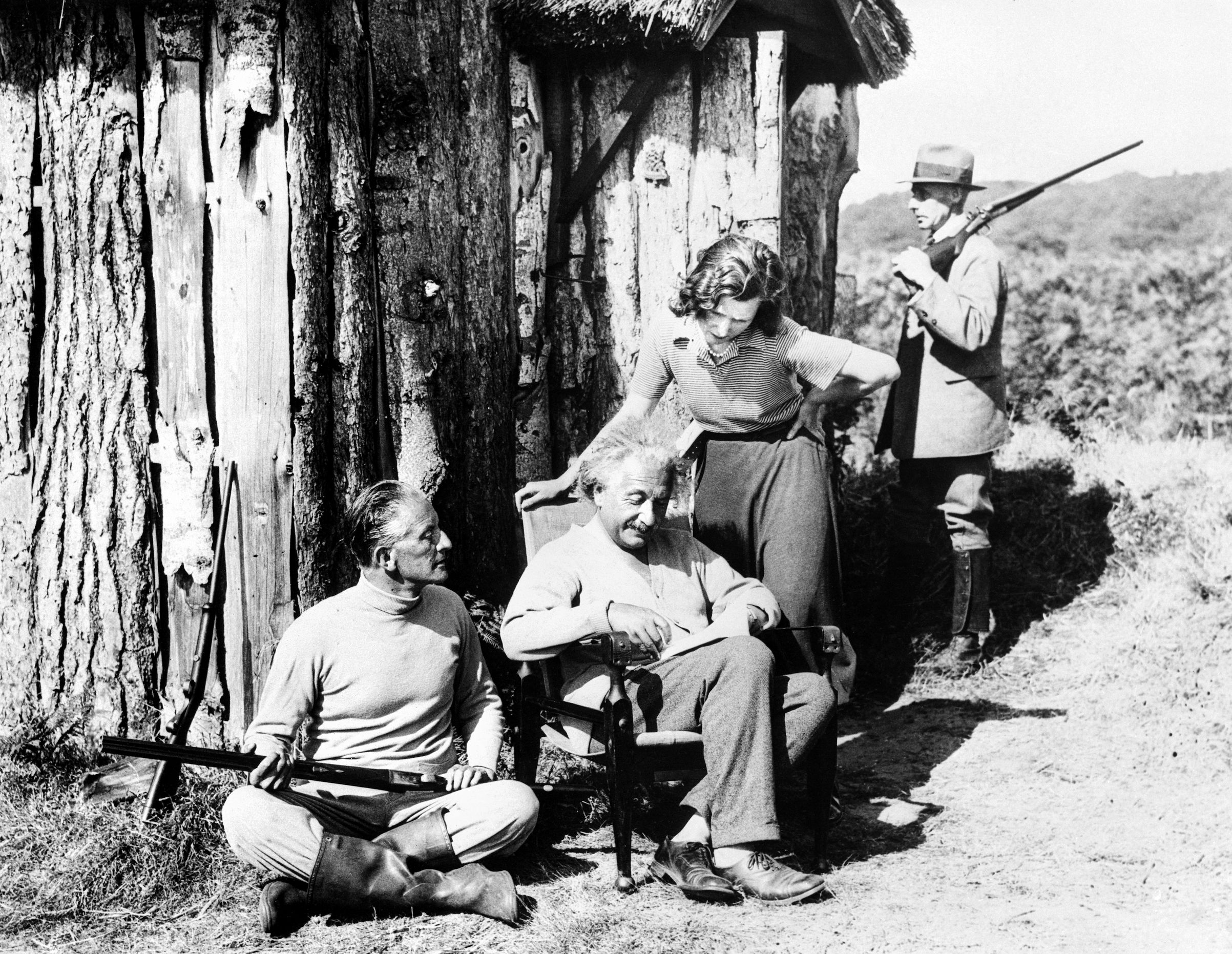 During his days in Great Britain, Albert Einstein is shown with his secretary, Miss B. Howard, and Commander Oliver Locker-Lampson, seated with a shotgun. The three are seen outside a holiday hut on the moors provided by Locker-Lampson. At the time, it was rumored that Hitler had placed a $5,000 price on Einstein’s head. After spending the summer of 1933 in Britain, Einstein relocated permanently to the United States.