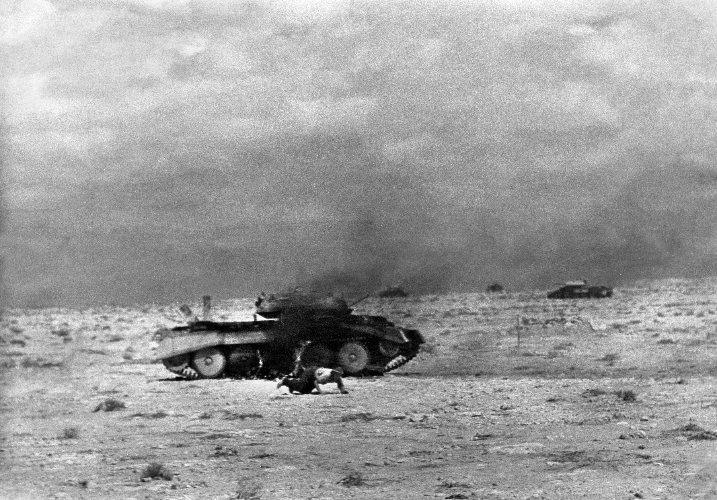  A British Crusader tank burns following a direct hit, as an injured crew member crawls away. Though more manueverable, the Crusader was under-armed and its light armor was no match for the Panzer III and Panzer IV medium tanks it faced in combat. Plagued by mechanical problems, it would not see combat after North Africa, where it was replaced as the main tank by  the M3 Grant and then by the M4 Sherman medium tanks, both supplied by the U.S. 