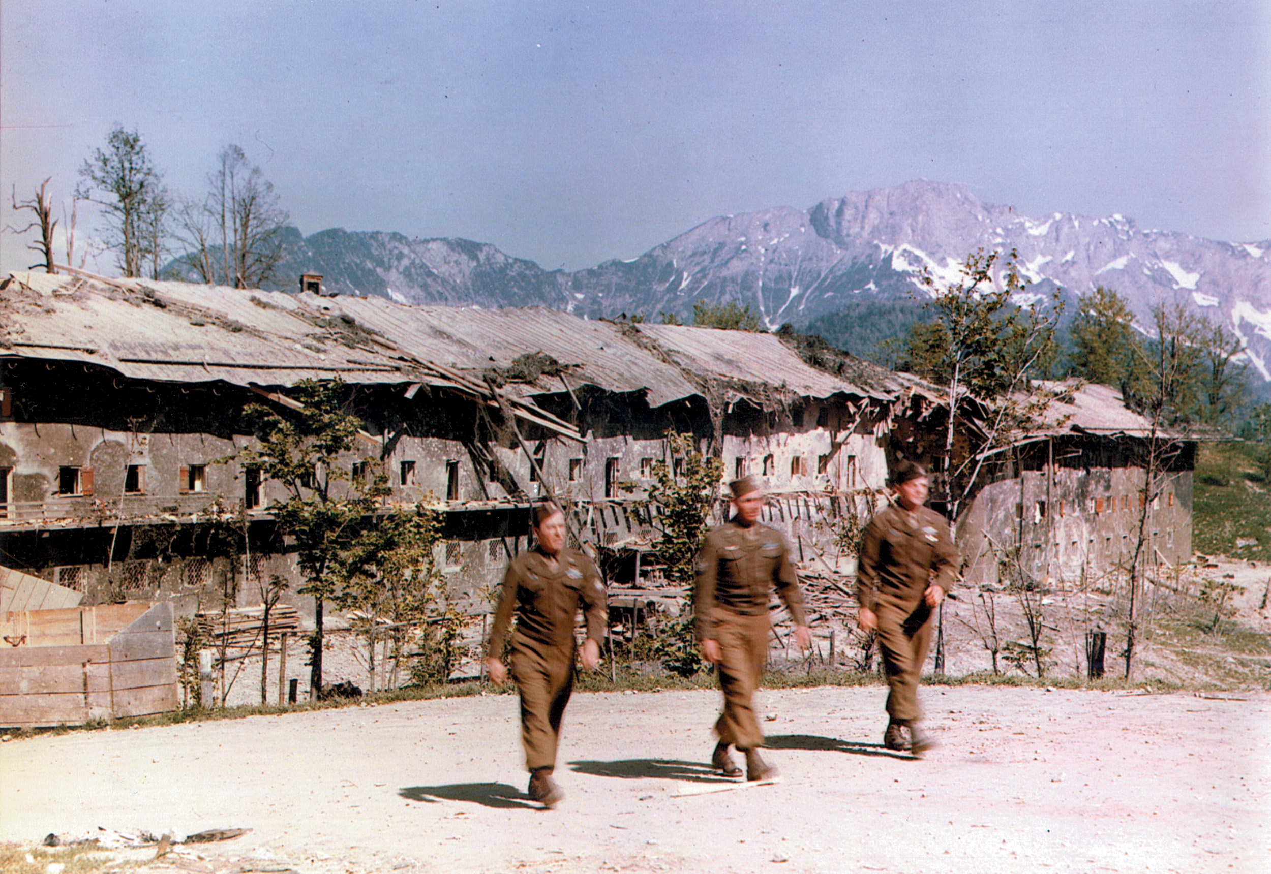 Three soldiers walk past the SS barracks on the Berchtesgaden grounds. The Royal Air Force bombed the barracks on April 25, 1945. A correspondent who visited the area reported, “The trees and shrubbery were gone, the grass was gone, there was just torn, brown earth and splintered rocks, a mockery of beauty and power.”