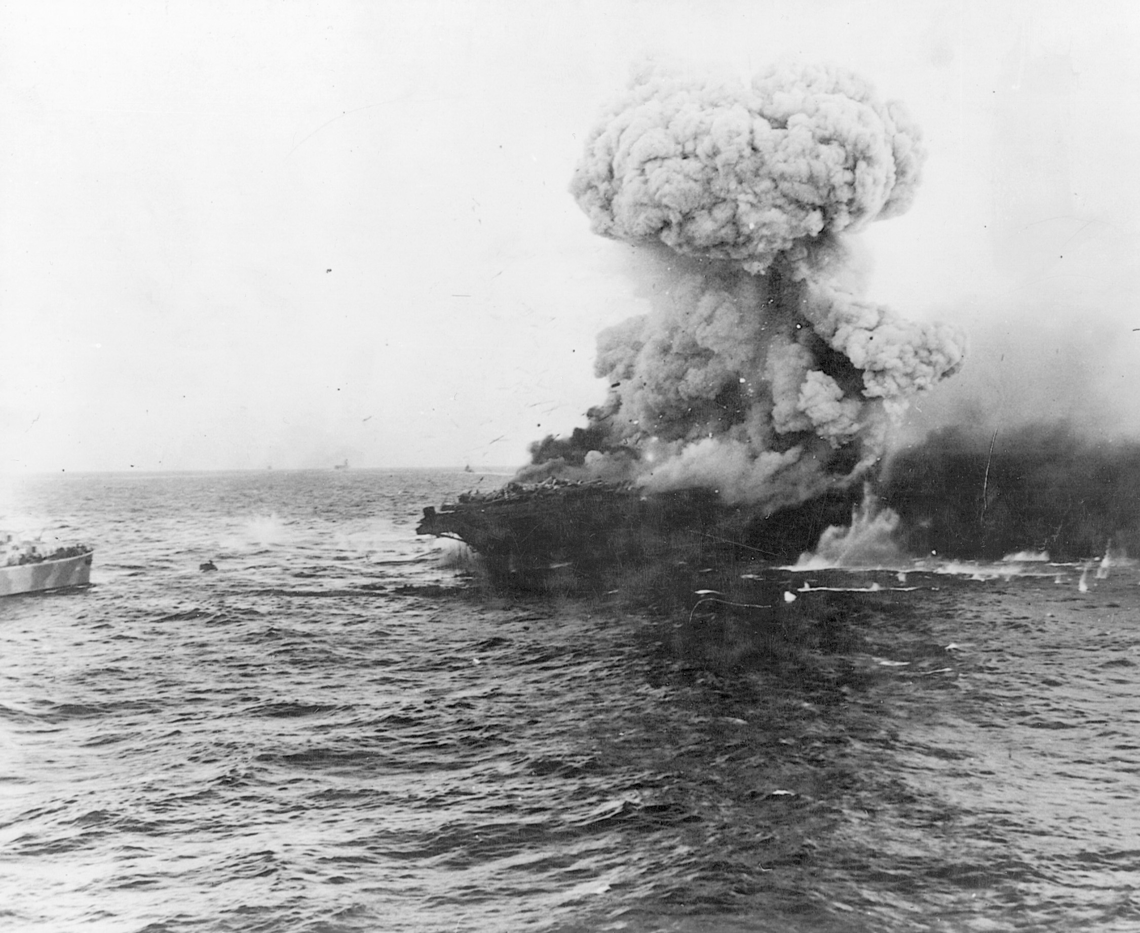 The aircraft carrier Lexington is engulfed by the mushroom cloud of a catastrophic internal explosion. Efforts to save the Lady Lex failed, and the carrier settled to the bottom of the Coral Sea.