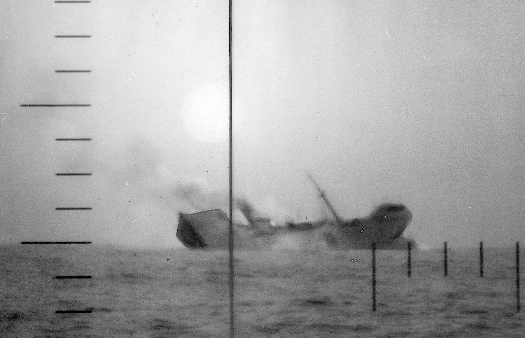 In a periscope view from the American submarine that has torpedoed it, a Japanese freighter breaks in half before sinking.