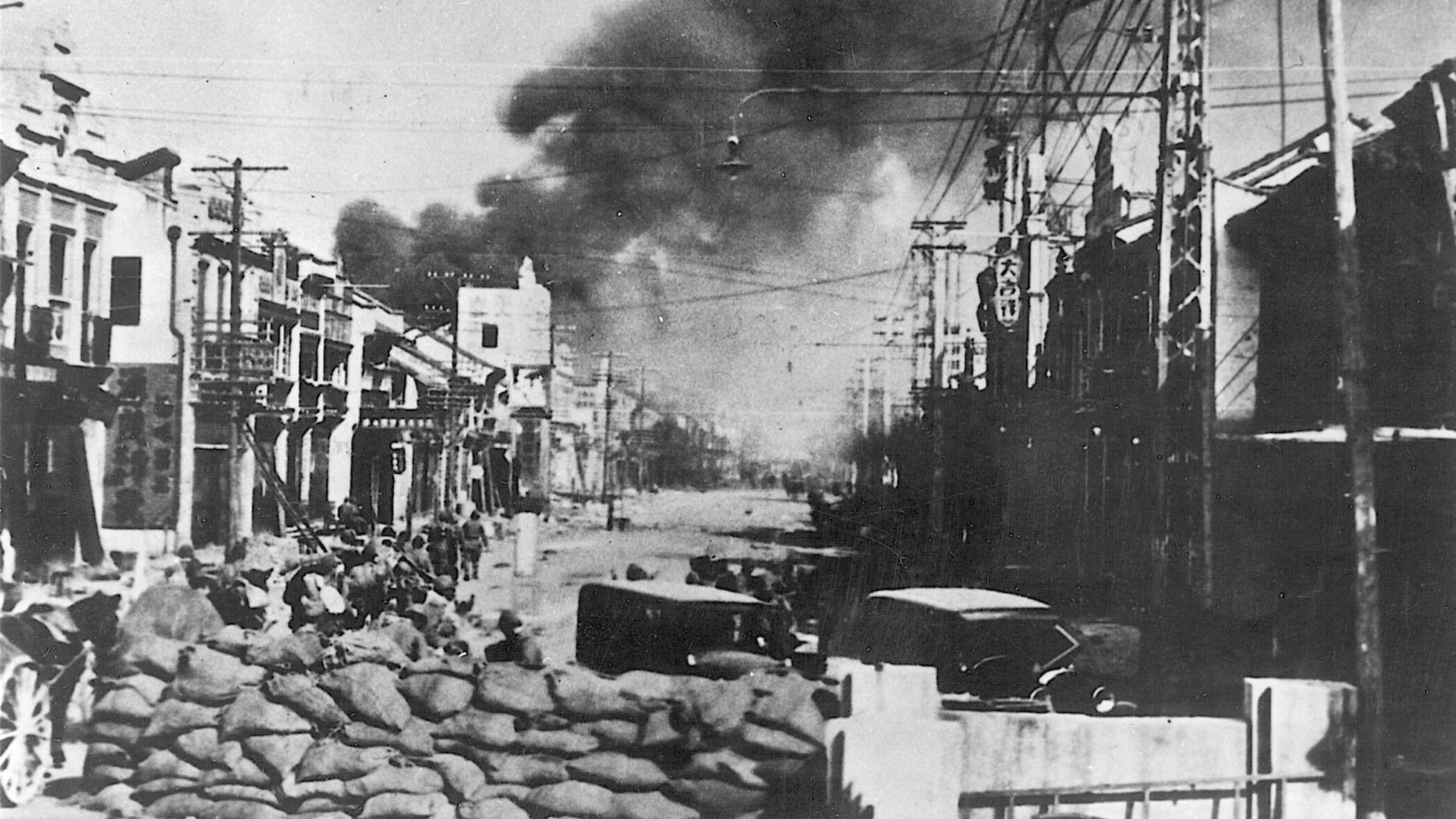 Smoke billows from a raging fire in the distance as Japanese troops occupy a barrier in a Nanking street, which was once defended by Chinese soldiers. The 1937 Rape of Nanking was a tragic chapter in the history of Sino-Japanese relations.