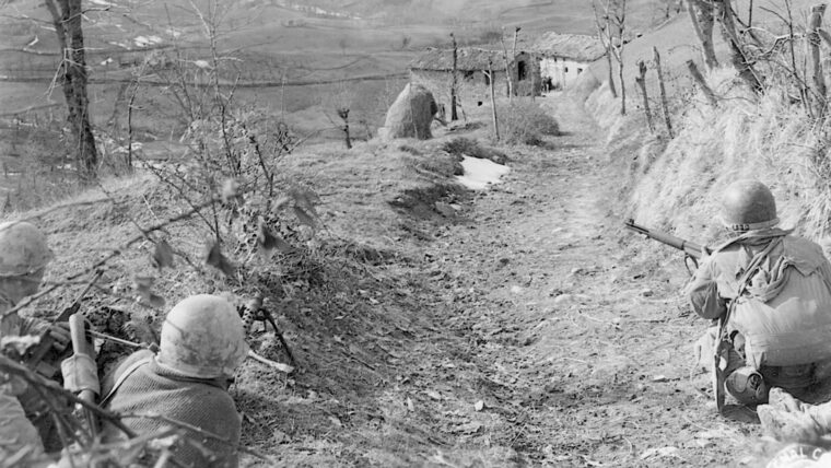 Soldiers of the 10th Mountain Division fire at German troops occupying barns in the rugged mountains of northern Italy.