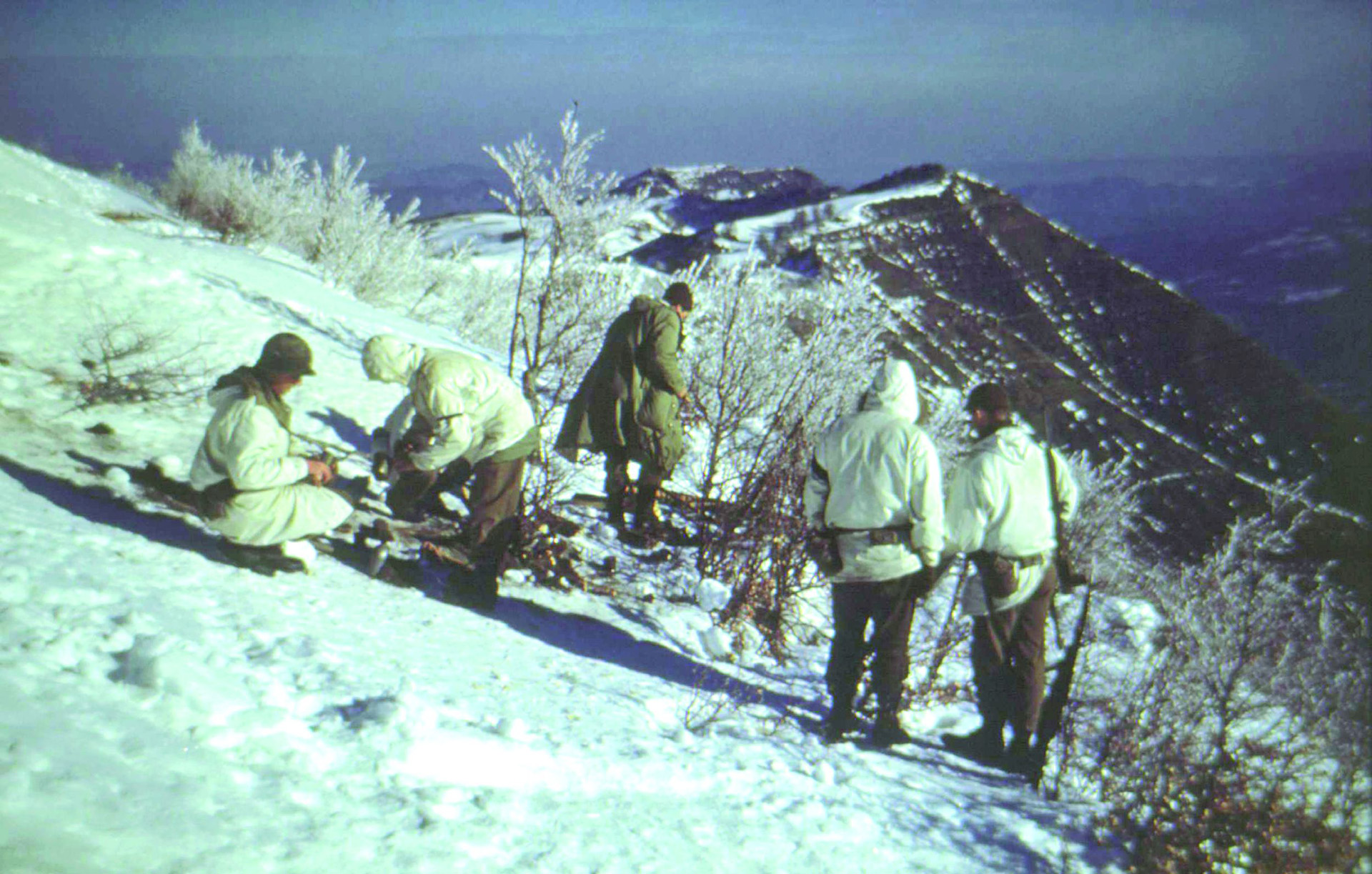 During a winter training exercise, 10th Mountain soldiers pause to rest on a steep slope.