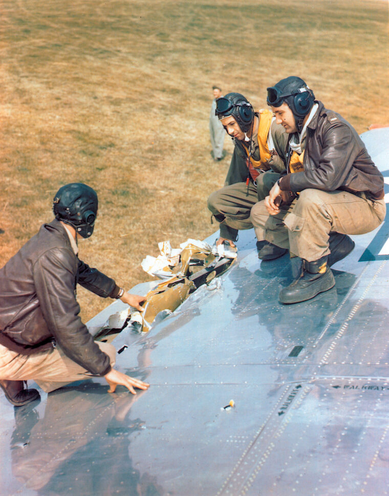 Crewmen of the B-17 dubbed “Peacemaker” view battle damage to a wing of their aircraft after safely returning to their base in England.