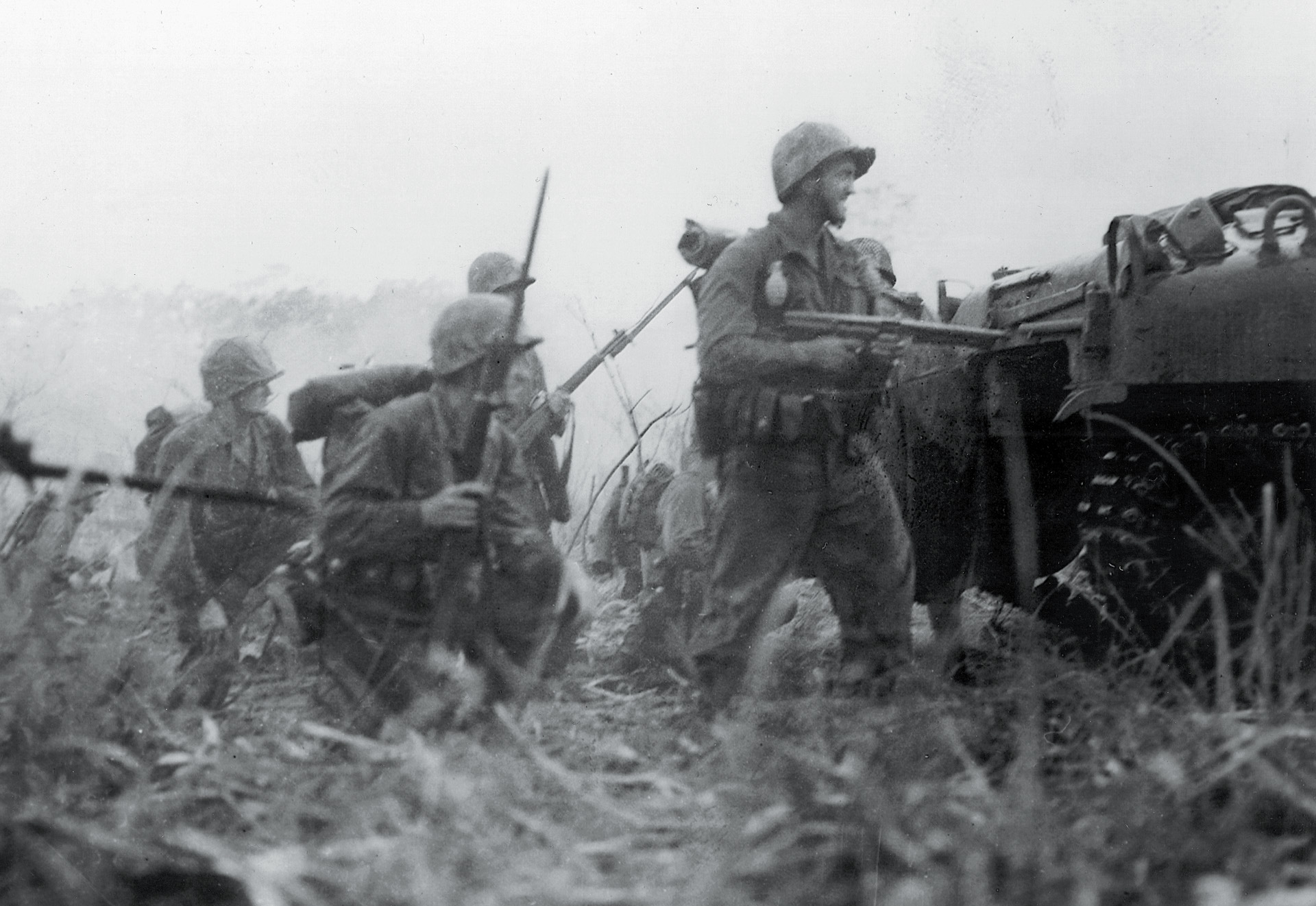 Weapons at the ready, a group of Marines is covered by a tank during an advance in the jungle near Cape Gloucester.