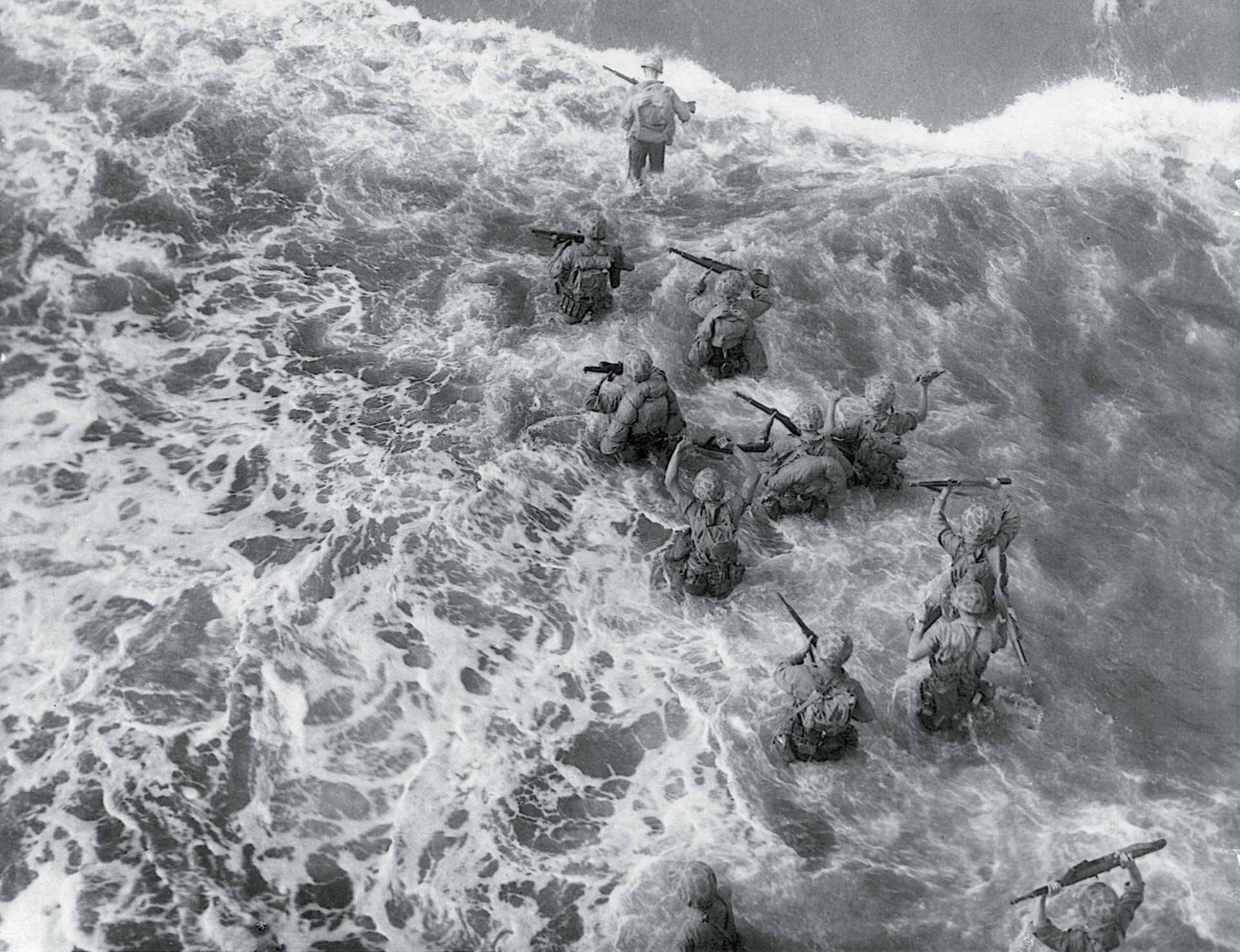 Their rifles held high out of the surf, Marines wade ashore at Cape Gloucester on December 26, 1943.