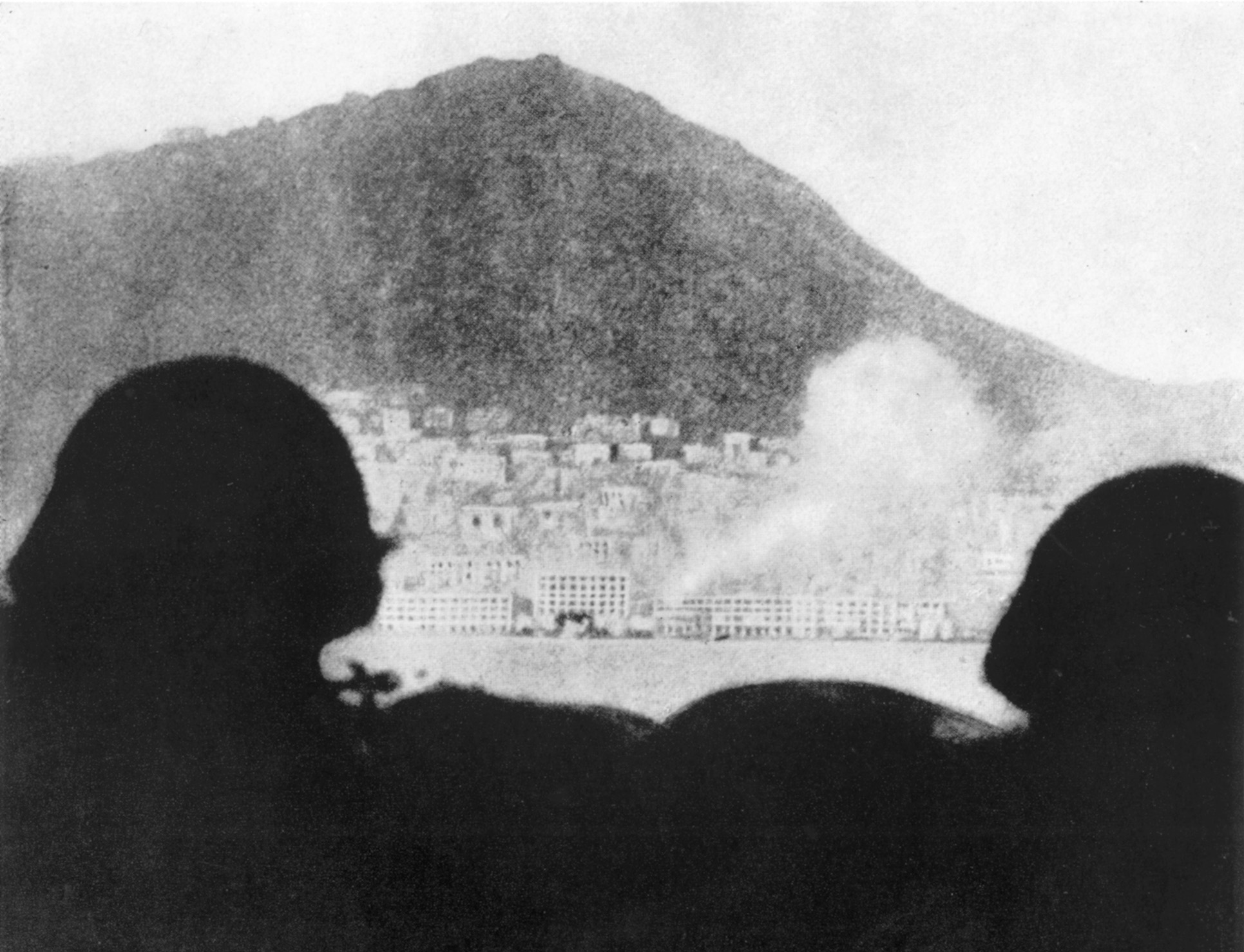 Japanese soldiers watch from Kowloon as their shells fall on Victoria.
