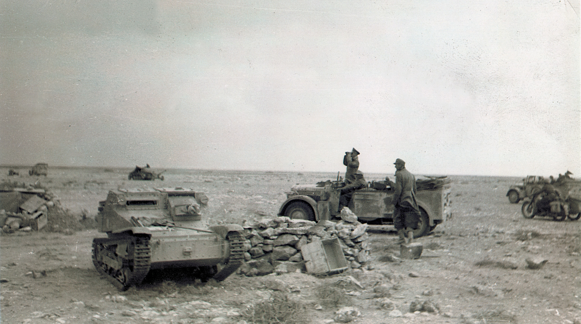 An abandoned Bristish Sten gun carrier sits nearby as Field Marshal Erwin Rommel surveys the ground before elements of his vaunted Afrika Korps.