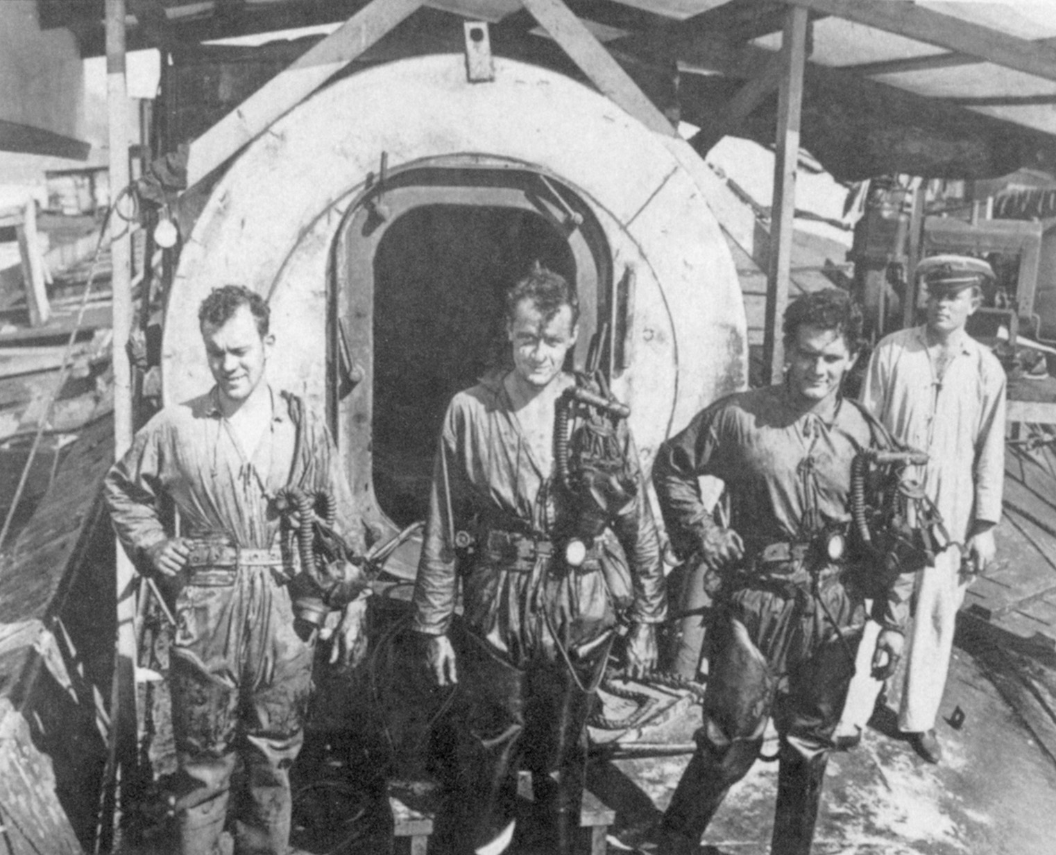 Divers pose in front of a decompression chamber during salvage efforts at Pearl Harbor.