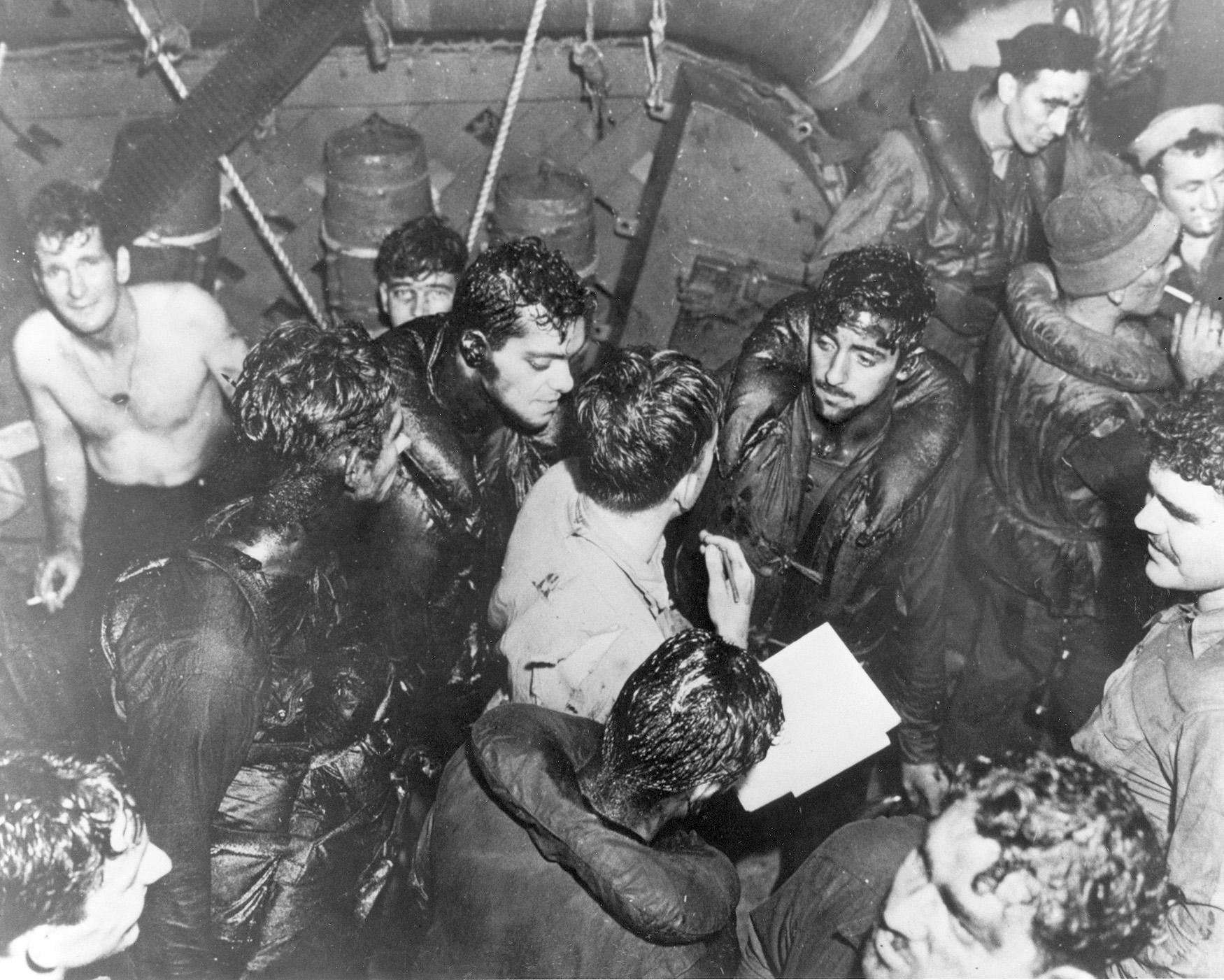 Wet and oiled sailors of the torpedoed cruiser Helena take what comfort they can on the decks of their rescuer, the destroyer Nicholas.
