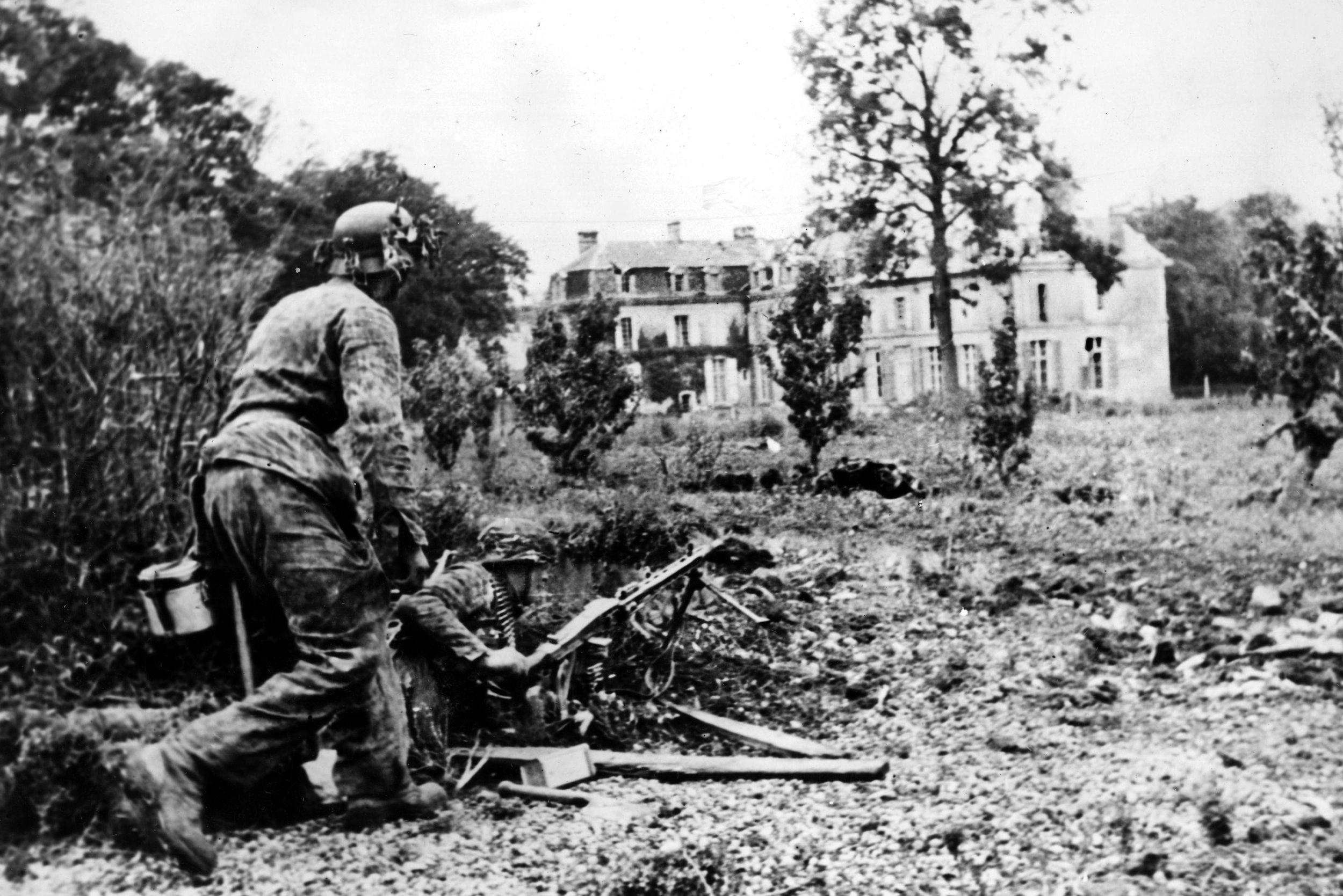 Two German grenadiers of the 12th SS Panzer Division Hitlerjugend man a defensive position in Normandy with an MG-42 machine gun. The 12th SS fought doggedly in the defense of Caen and during the German retreat from Normandy.