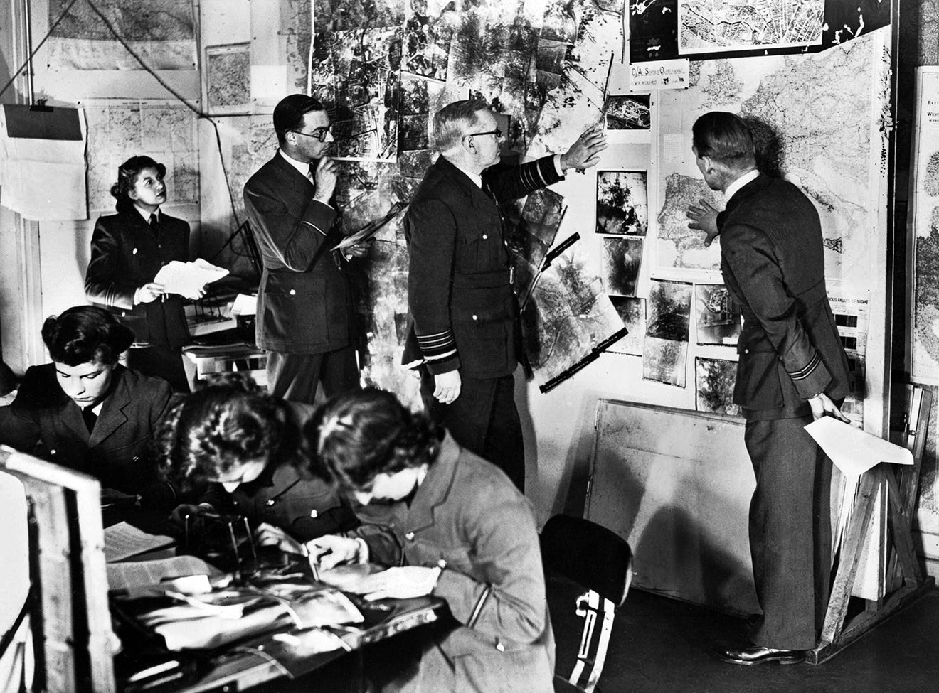 During a meeting at his Bomber Command Headquarters in High Wycombe, Air Chief Marshal Sir Arthur “Bomber” Harris examines reconnaissance photos from a raid on Nazi-occupied Europe.