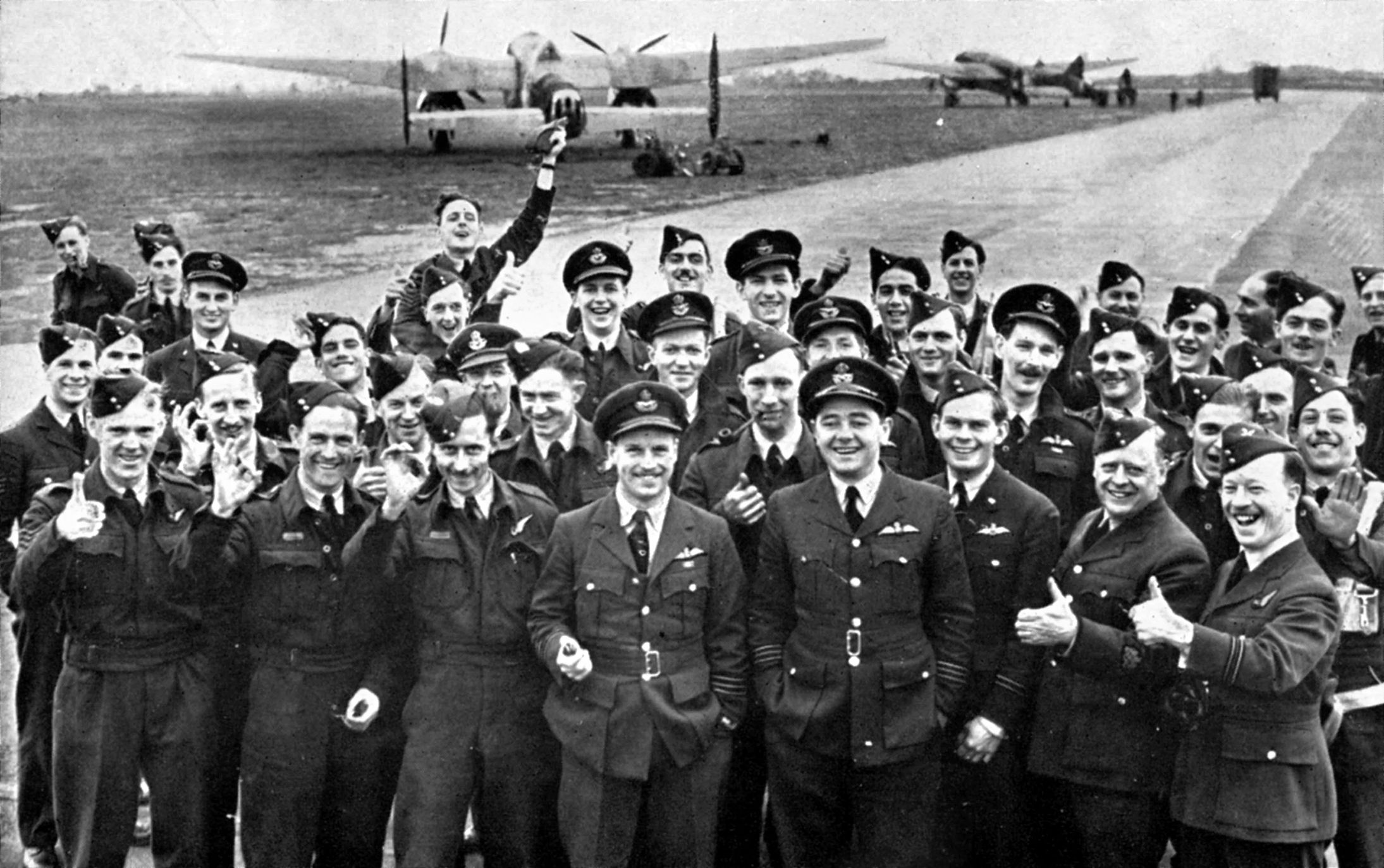 Their Avro Manchester bombers parked in the background at RAF Coningsby, Lincolnshire, and soon to be replaced by the hefty Lancaster, members of No. 106 Squadron RAF celebrate their return from the 1,000-plane raid against Cologne. Among those pictured is the squadron commander, Wing Commander Guy Gibson, standing in the center of the front row. Gibson later gained fame and received the Victoria Cross for leading No. 617 Squadron in the famed "Dambuster" raid a year later. He was killed in action in 1944.