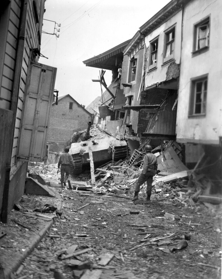 A Tiger II tank of Kampfgruppe Peiper lies wrecked and abandoned after running into a house in the Belgian town of Stavelot, where U.S. soldiers put it out of action permanently. The tank belonged to the 501s Heavy SS Battalion, a component of Kampfgruppe Peiper, which was denied entry into Stavelot by American combat engineers for a critical period during the Battle of the Bulge.