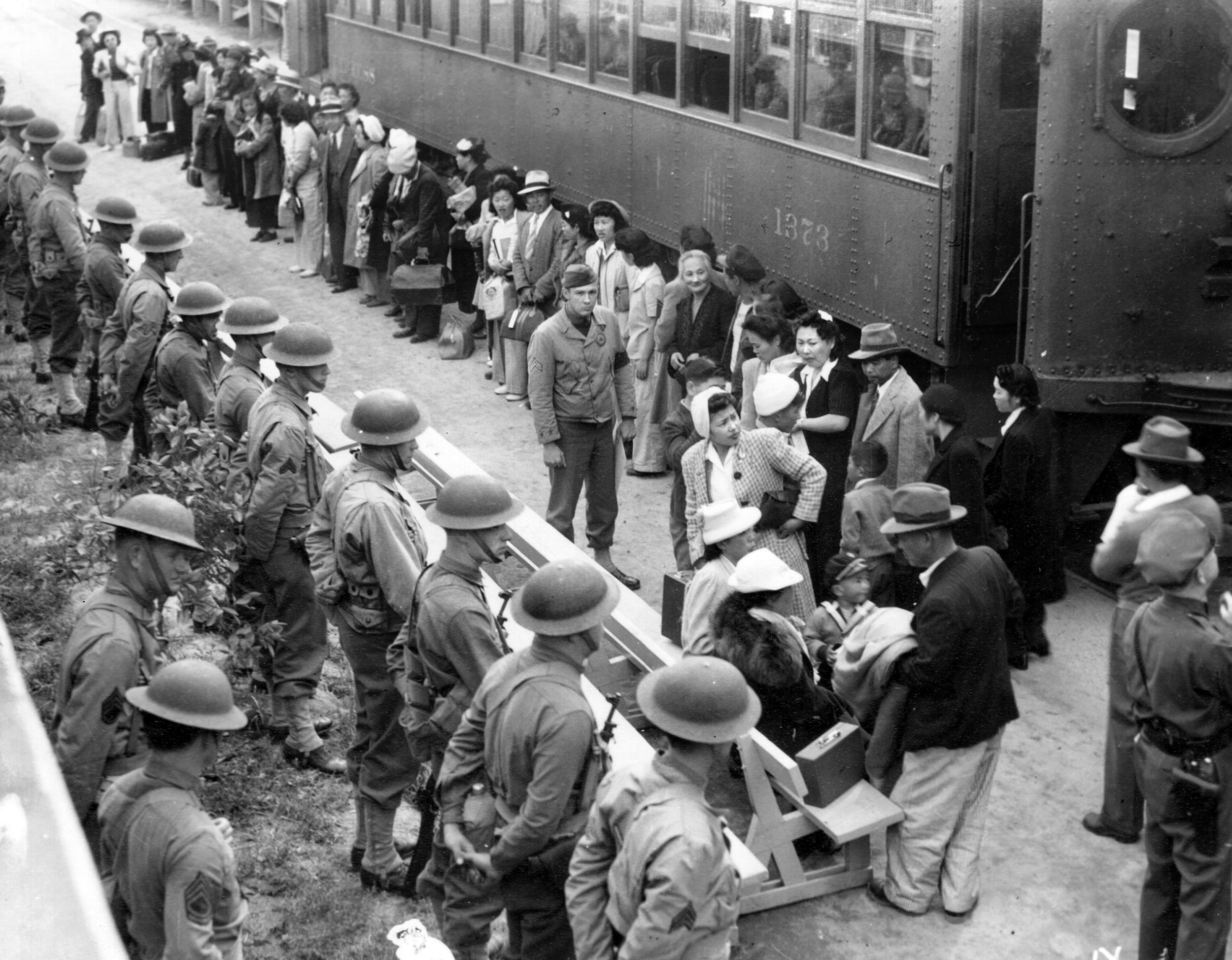 Japanese-Americans await orders to board a train to a resettlement camp during the early days of U.S. involvement in World War II.