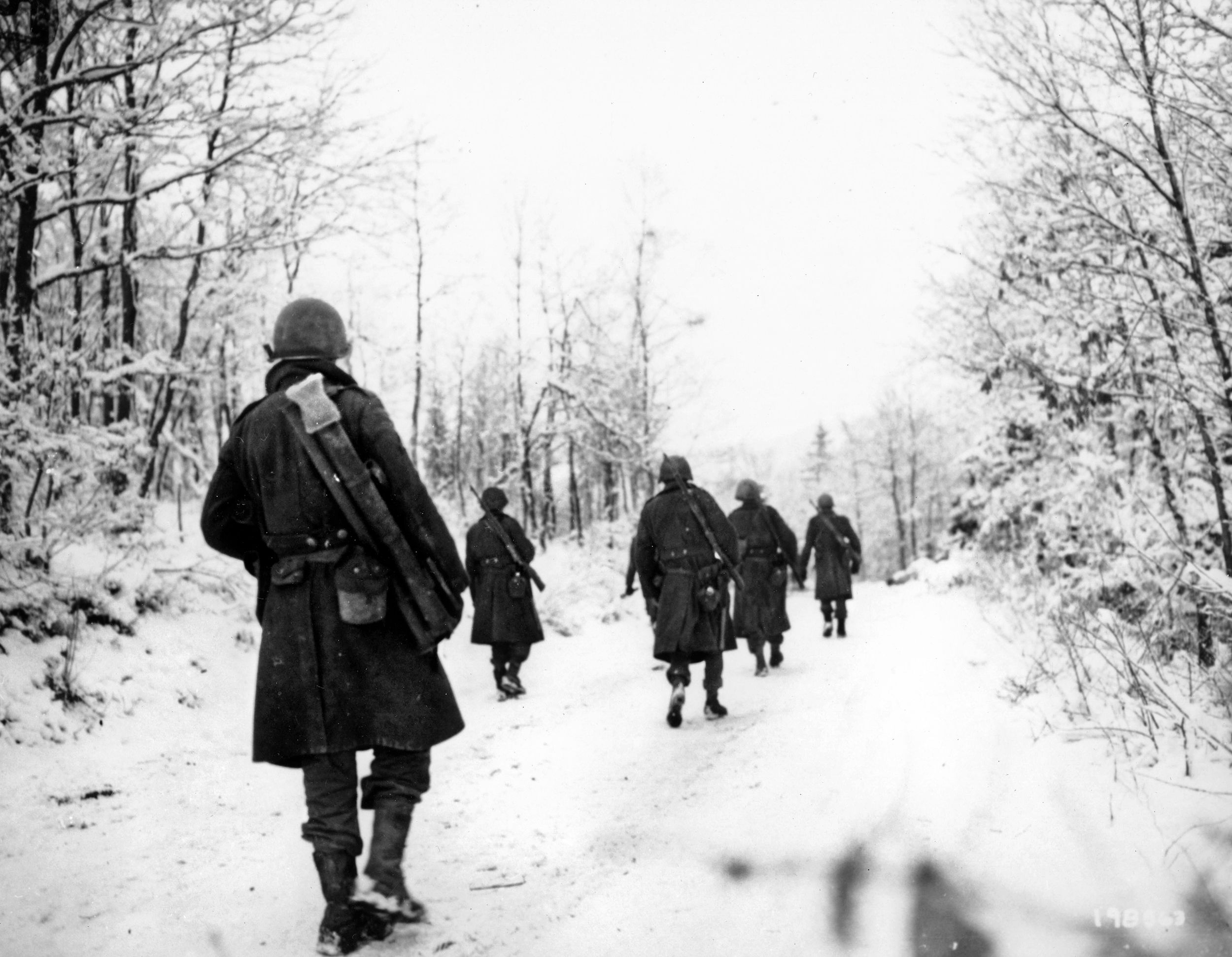 In this wintry photograph, soldiers of Company I, 333rd Infantry Regiment, 84th Division, advance along a road covered in snow and ice near Forge à la Plez, Belgium. The 84th Division helped to slow the German assault during the Battle of the Bulge and then reduce the salient that had developed.