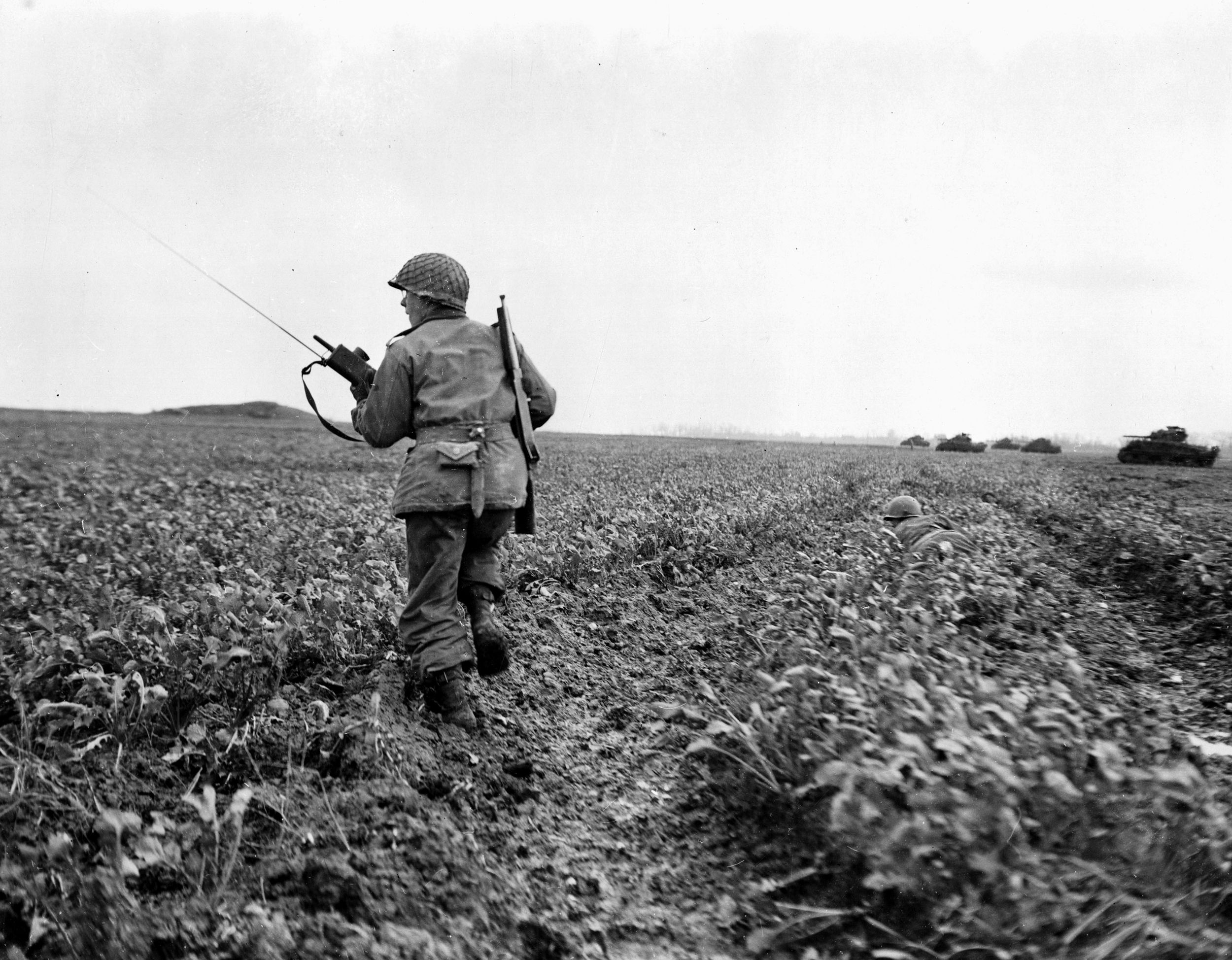 Accompanying M4 Sherman medium tanks into an open field, soldiers of the 333rd Infantry Regiment advance toward a German pillbox near the town of Prummern, Germany. The 84th Division trained American soldiers for combat and then also deployed to Europe.