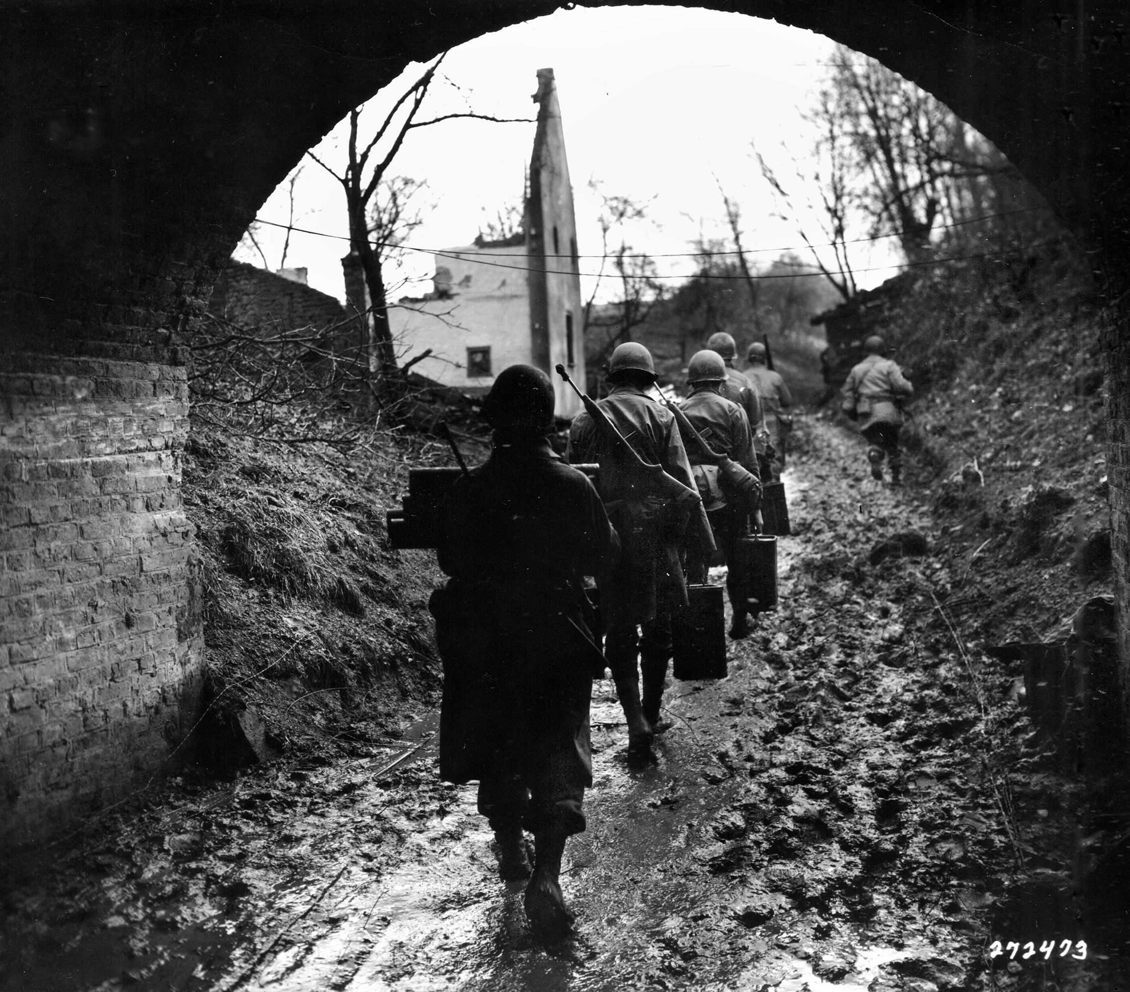 Trudging along a muddy road, American soldiers of the 333rd Infantry Regiment (84th Div.) advance near Suggarath during the fight for control of the German city of Würm. This photograph was taken in the early stages of the battle in late November 1944. 