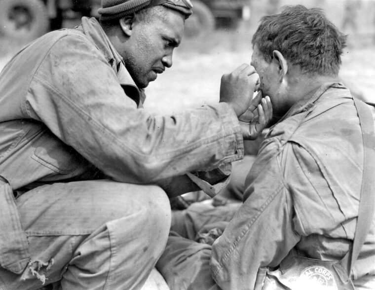 Private First Class Warren Capers removes shrapnel from the face of a wounded soldier on D-Day+2, June 8, 1944. Capers, a member of the 320th Barrage Balloon Battalion, was recommended for the Silver Star for his heroism in Normandy. Capers and his comrades set up an aid station on D-Day and treated an estimated 330 wounded soldiers on that day alone. 