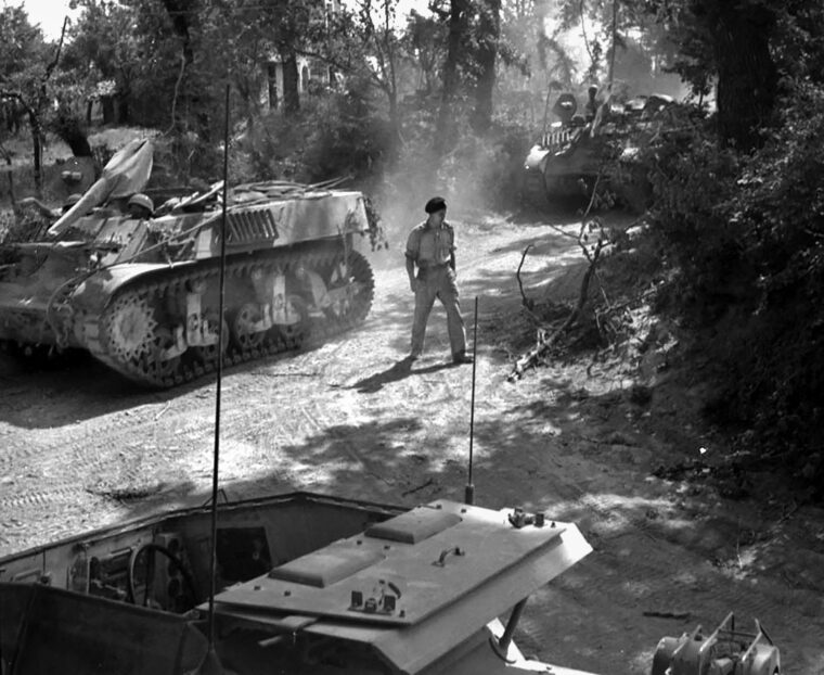 Two Stuart light tanks, nicknamed “Honeys” as their turrets have been removed and .50-caliber machine guns have been mounted, pause at a crossroads in Italy during the 1944 campaign. These modified armored vehicles were utilized primarily for reconnaissance. 