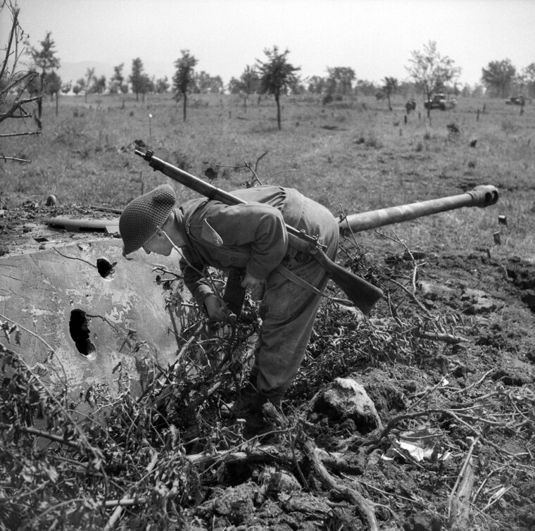 A Canadian soldier pauses to inspect a panzerturm, the turret of a PzKpfw. V Panther with its 75mm cannon mounted in a fixed position, such as this concrete bunker. Such defenses were encountered during the assault against the Hitler Line. 