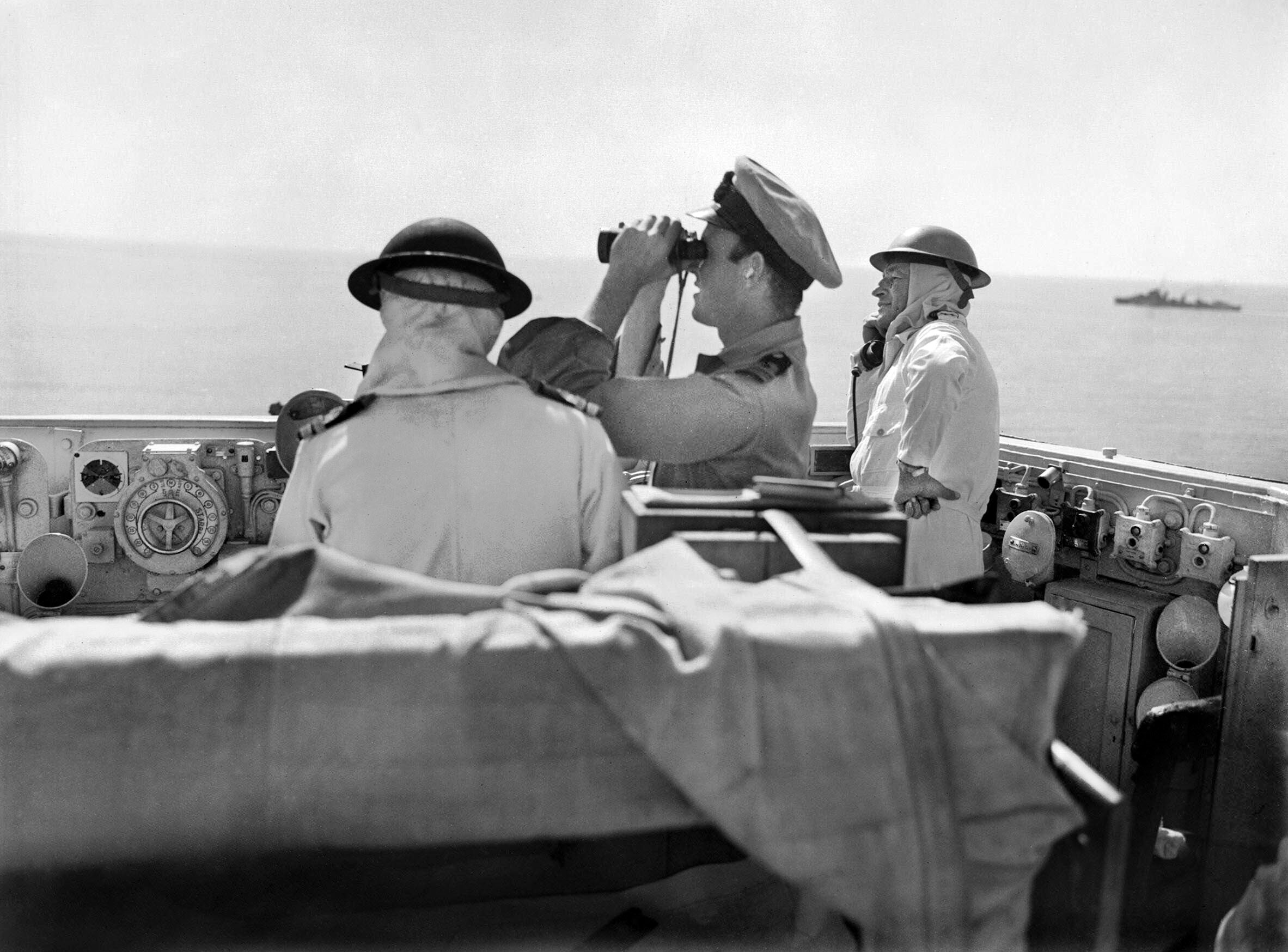 Captain Herbert Packer, right, on the bridge of Warspite, observes the bombardment of the Italian mainland, September 1943. Packer, who had also served aboard the ship during World War I, and another sailor are wearing anti-flash coveralls. 