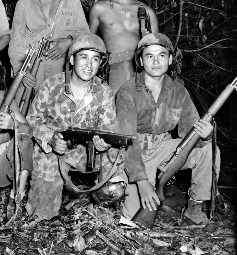 During fighting on the island of Bougainville in the Pacific in 1943, a Navajo code talker holds a Reising submachine gun at left. The Reising performed poorly during World War II and was generally loathed by those who were issued the weapon.