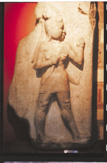 A helmeted Hittite warrior wields a battle ax and wears a short sword at his side.