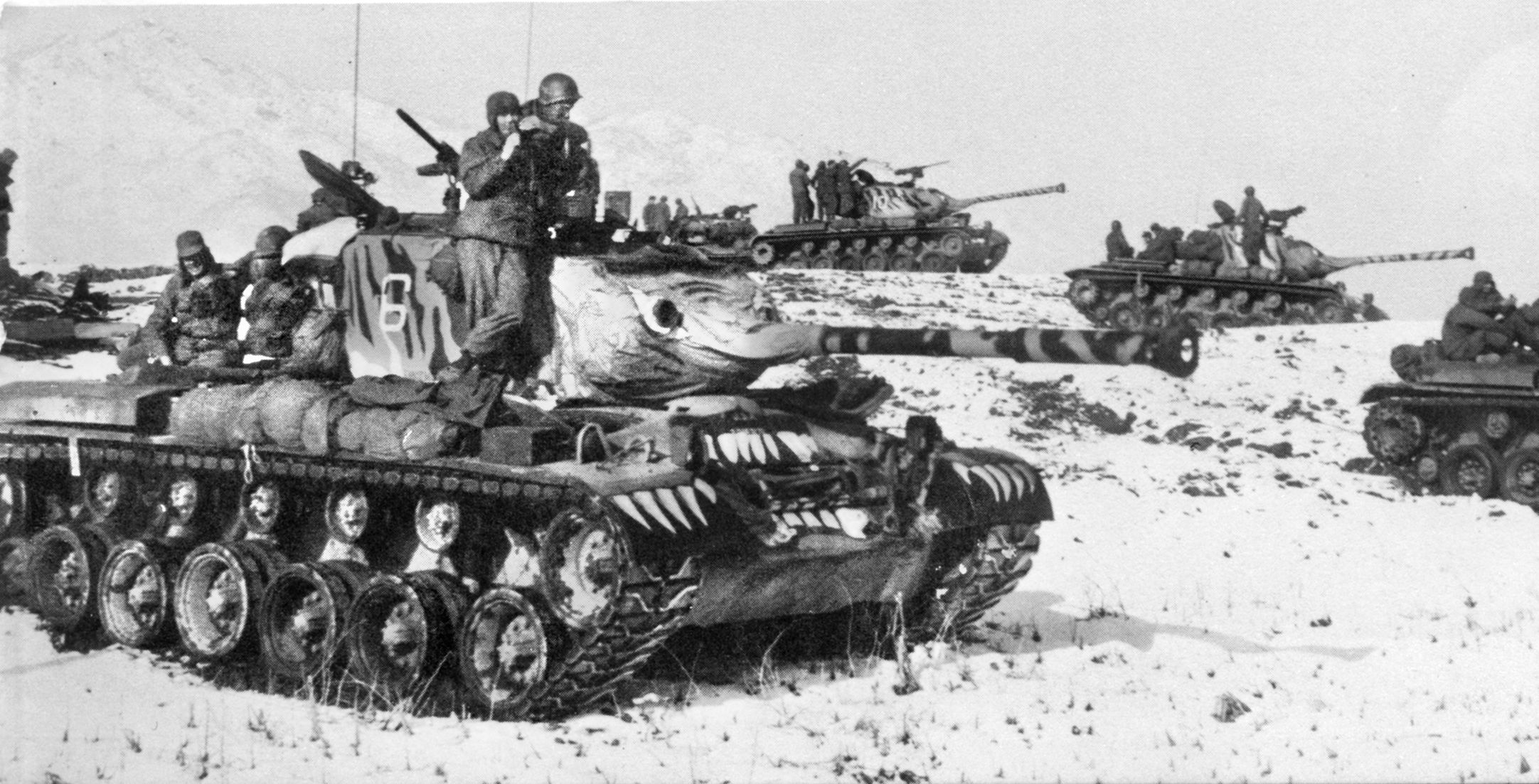 GIs in Korea catch a ride on M26 Patton tanks from the 6th Armored in March, 1951. Captain Lewis Millett’s 1st and 3rd platoons of the 27th Infantry Regiment “Wolfhounds” were riding north atop tanks when they spotted the enemy atop what would become “Bayonet Hill.”