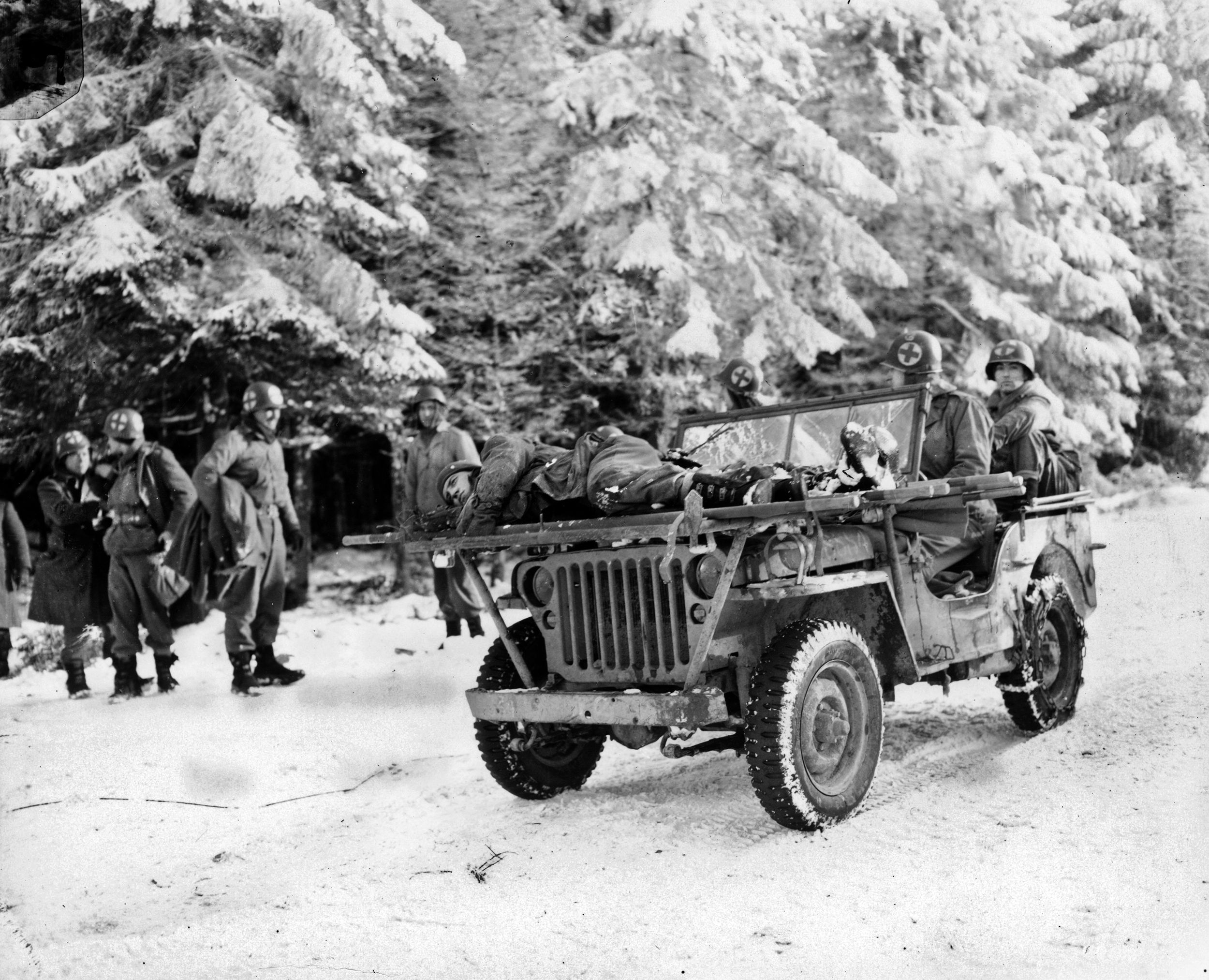 Medical personnel arrive at an aid station with wounded aboard. During the harsh winter months, Jeeps were often used to transport wounded men due to wintry road conditions. This photo was taken in January 1945.