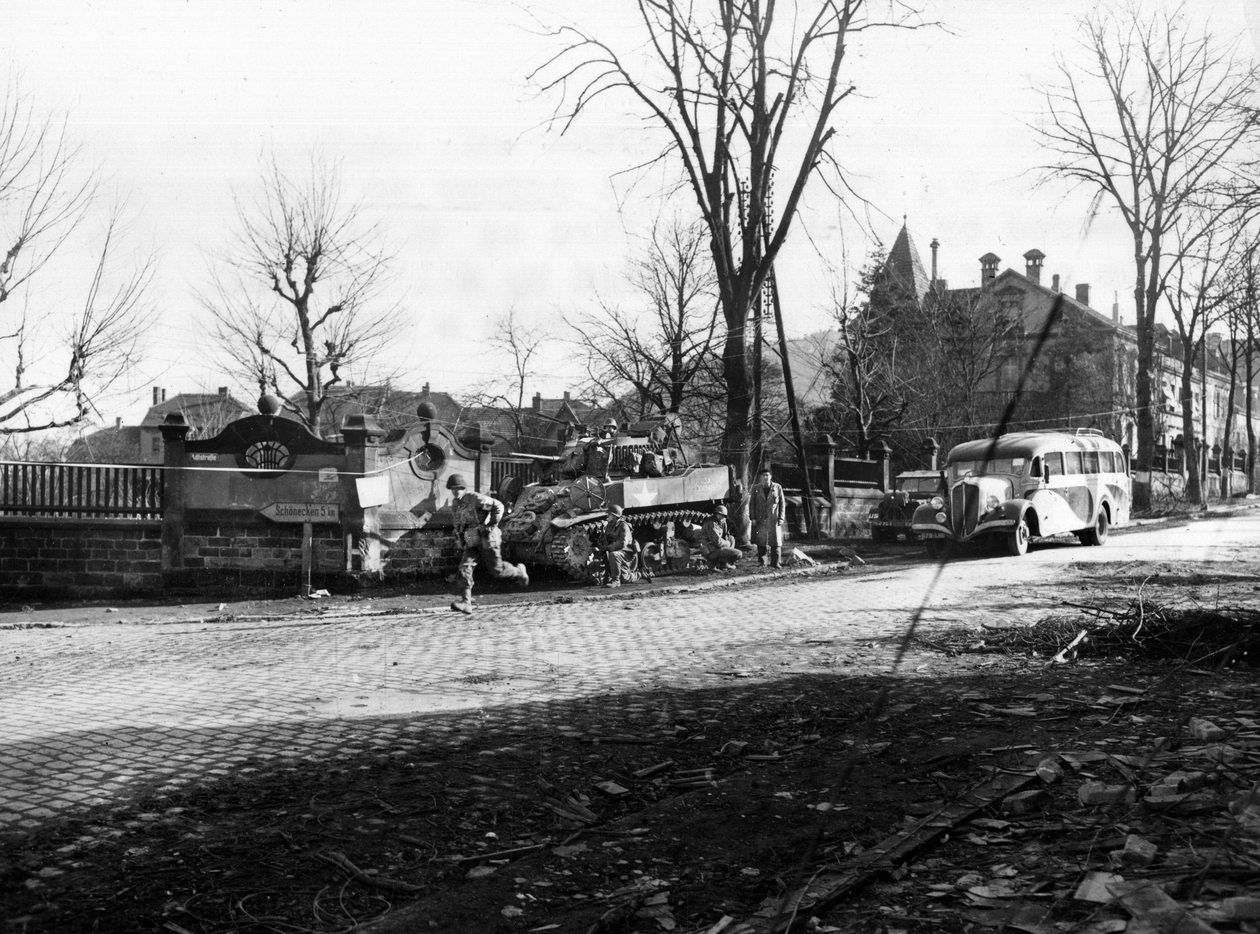 Covered by machine-gun fire from the light tank behind him, a medic of the 274th Infantry Regiment dashes forward at a contested intersection. During World War II, medics often displayed valor under fire and saved lives in the process.