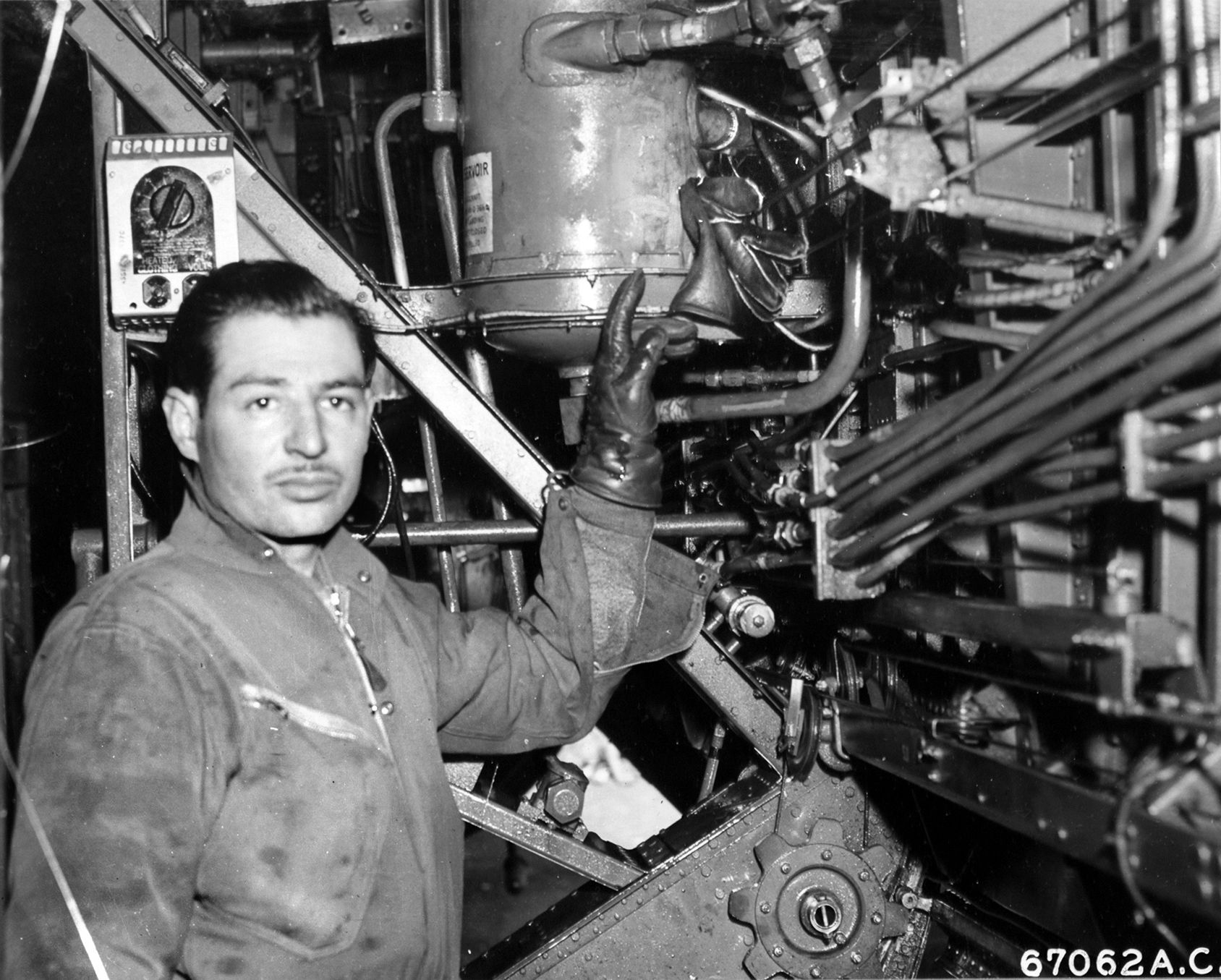 Sergeant Edward Vigil, assistant engineer aboard a bomber during the B-24 raid on Steyr on April 2, 1944, points to his glove, stuffed into a hole created by a fragment from a German 20mm shell. The quick-thinking Vigil used the glove to stop the leaking of hydraulic fluid, allowing the bomber to lower its landing gear and safely return to base.