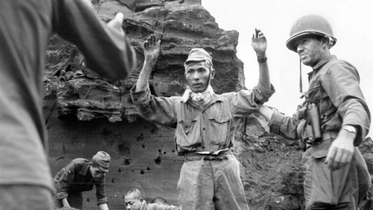 Assisted by a Japanese POW (left), Japanese soldiers emerge from a cave to surrender to American troops on April 5, 1945, a full 10 days after the island had been declared secure. After the U.S. Marines fought a bitter battle to take Iwo Jima, the 147th Regiment of the U.S. Army was tasked with rooting out some 3,000 diehard Japanese troops that had continued to resist.