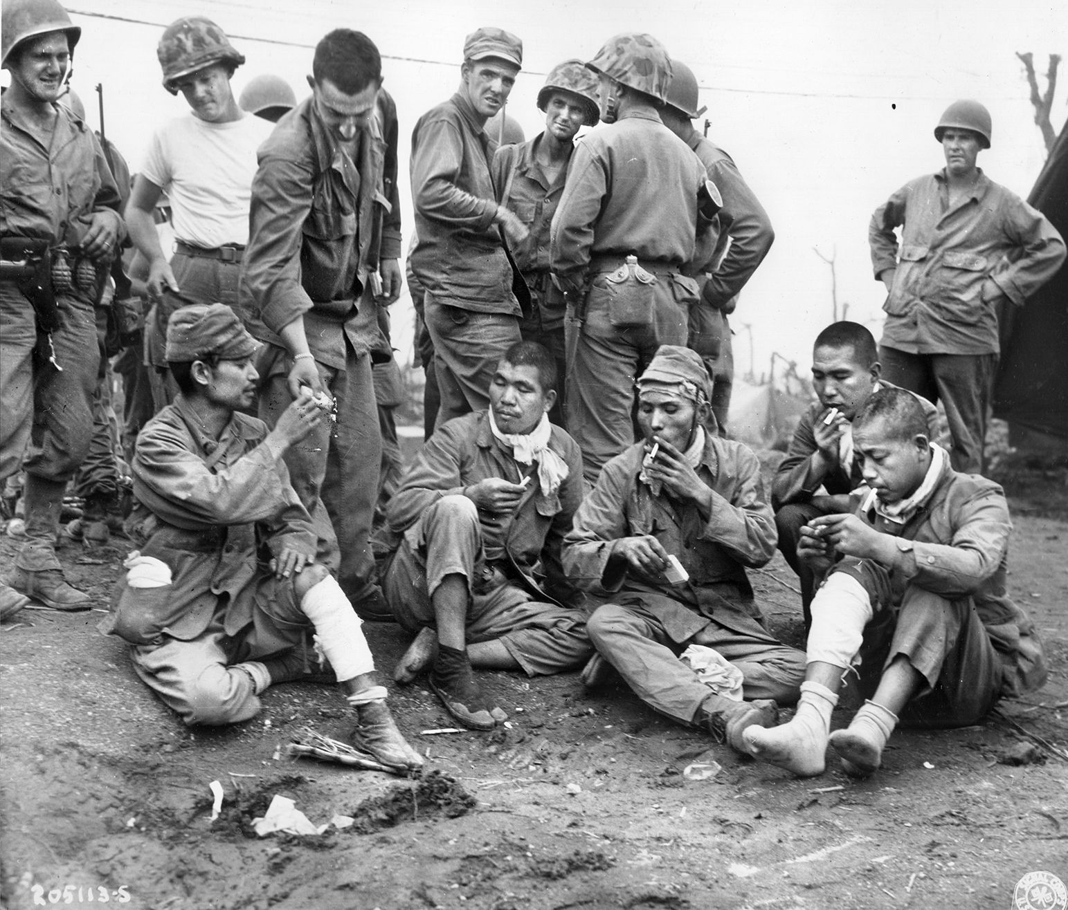 American soldiers share cigarettes with Japanese POWs on Iwo Jima. The “Cave Men” of the U.S. Army’s 147th Infantry Regiment completed the hazardous task of killing or capturing diehard Japanese soldiers hiding underground on the island after it was declared secure.