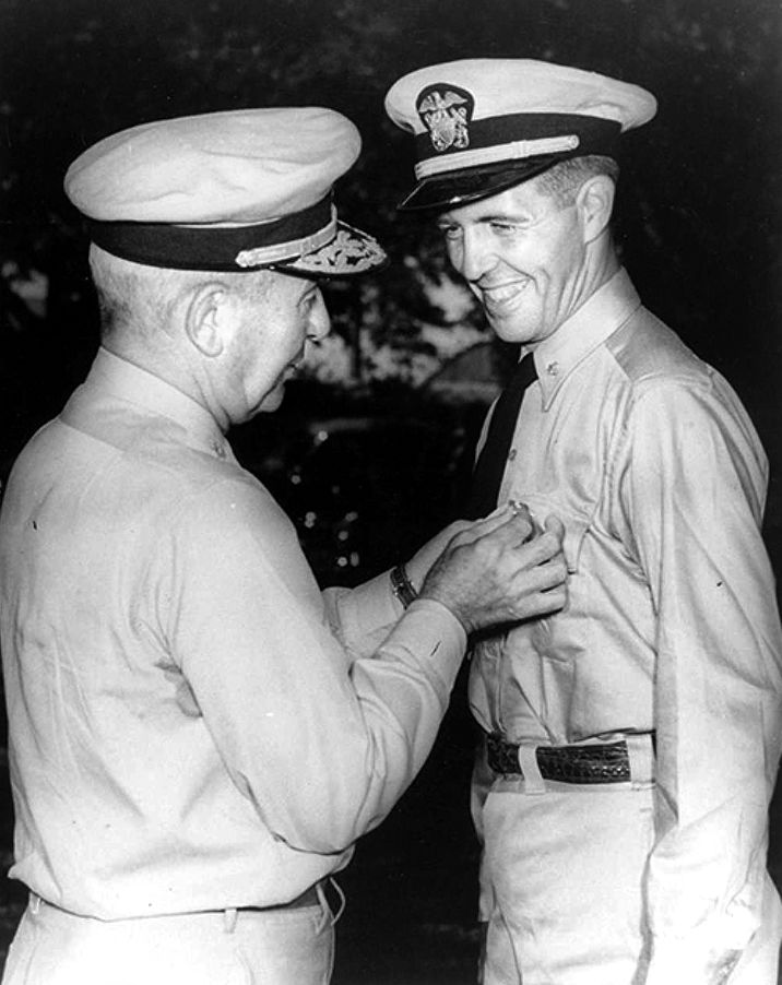 Lieutenant Commander Draper Kauffman receives his second Navy Cross for heroism during operations on the Japanese-held island of Saipan. Presenting the medal is his father, Adm. James L. Kauffman.