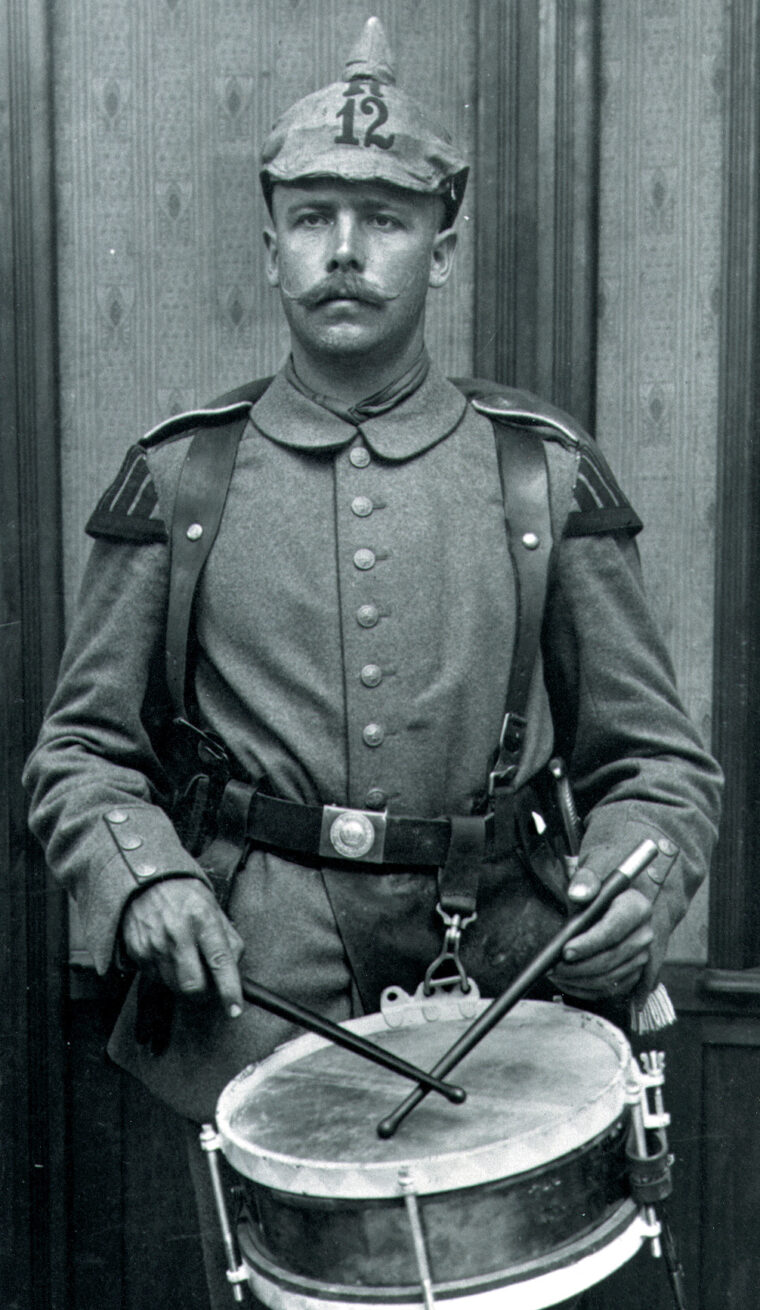 A drummer of the 12th Reserve Infantry regiment wears the 1910 field gray uniform with a fitted cotton helmet cover.