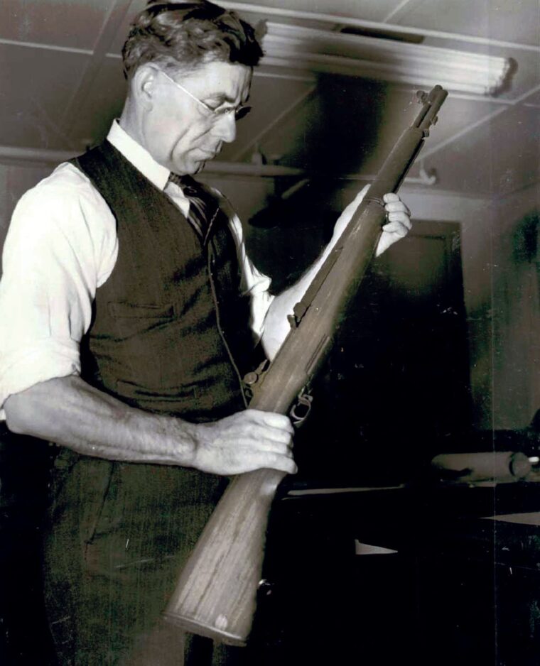 Firearms inventor John C. Garand poses with his most famous creation, the M-1 Garand infantry rifle. This photo was taken at the Springfield Armory as Garand was involved with production.