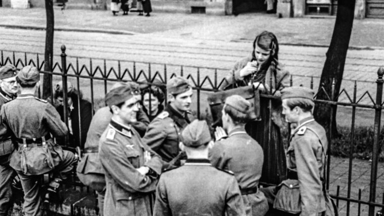 Sophie Scholl stands behind a fence at the Munich rail station before White Rose members Hans Scholl, Christoph Probst, Alexander Schmorell and Willi Graf depart for the Russian front in July 1942.