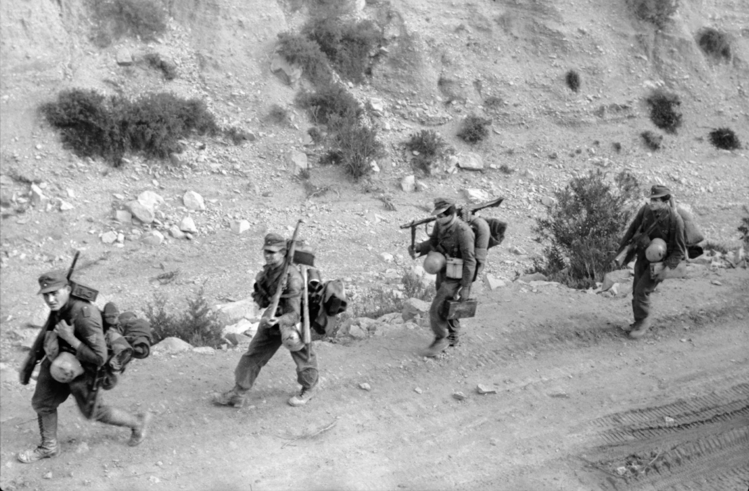 Heavily armed with rifles and machine guns, veteran Afrika Korps soldiers trek through the Tunisian desert in early 1943. Although they defeated the inexperienced Americans at Kasserine Pass in February, it would be the German expeditionary force in Africa that surrendered three months later.